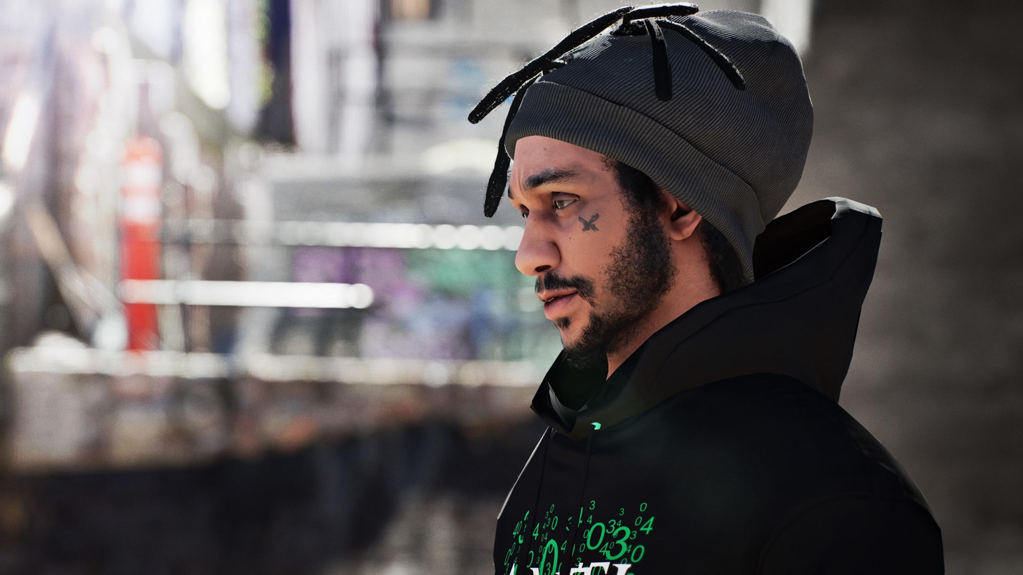 Ein Mann mit grauer Mütze und schwarzem Hoodie mit grünen Zahlen.