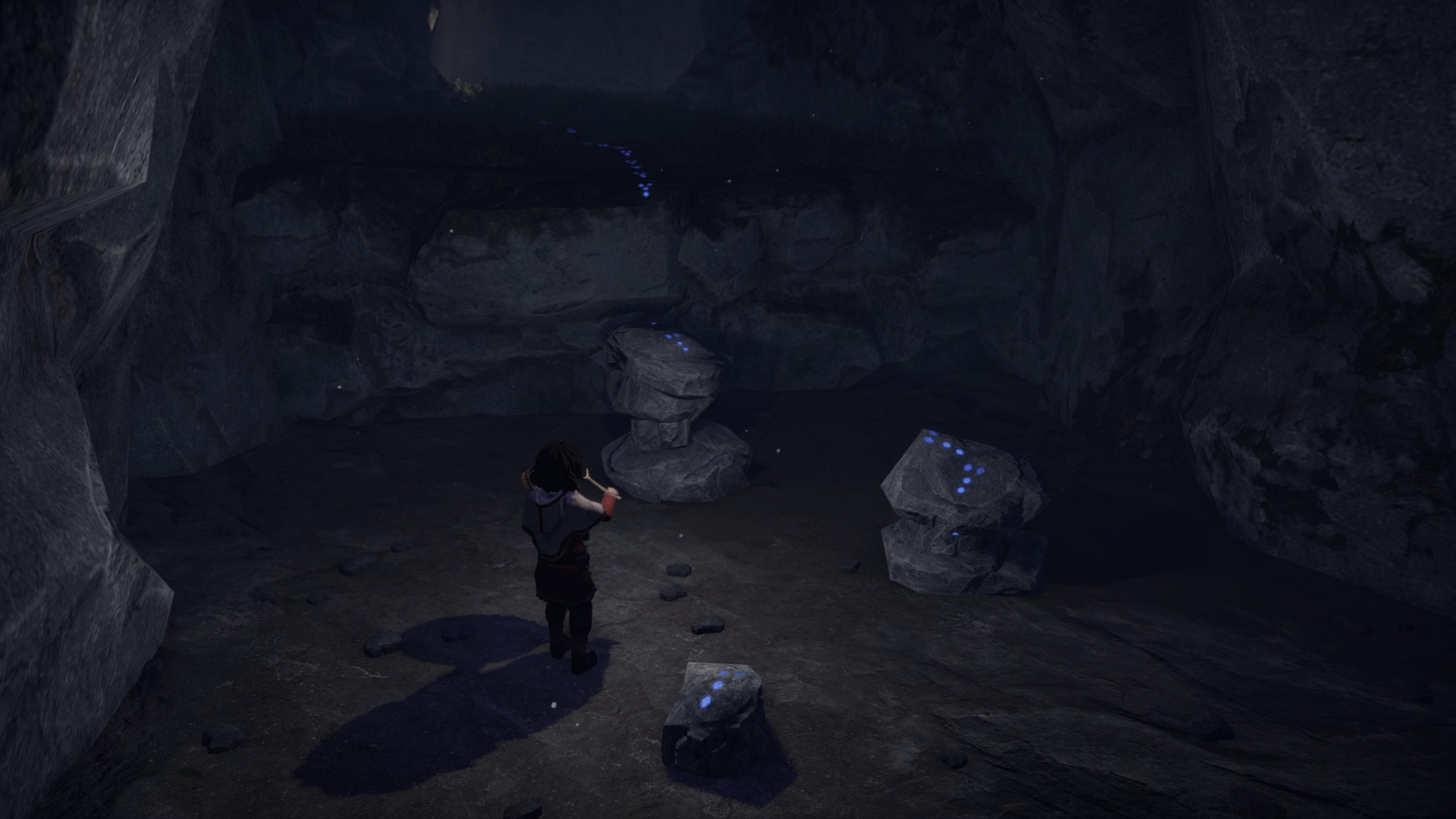 Un bambino in piedi in una grotta buia davanti a rocce con luci blu.