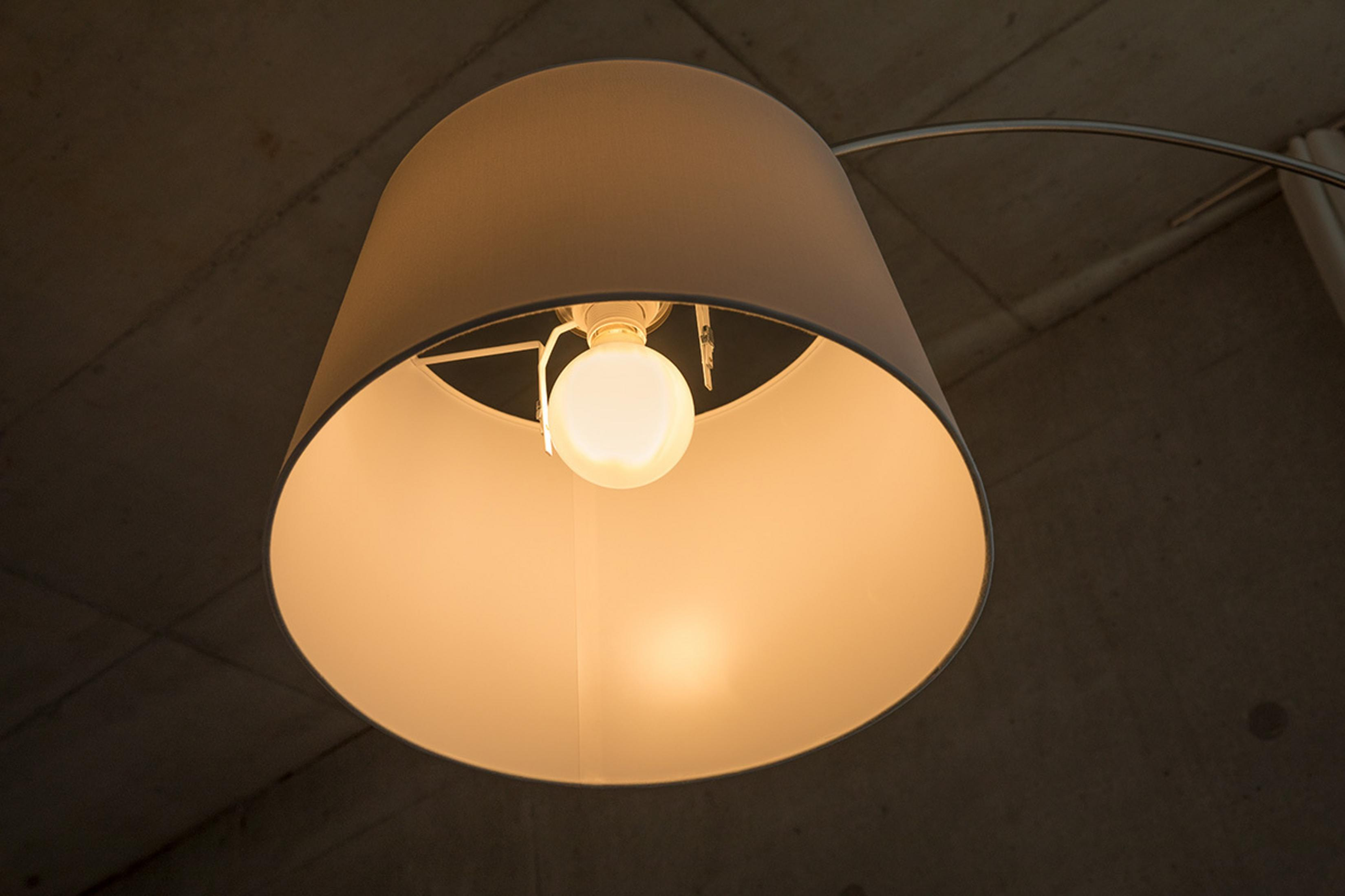 Podpalona żarówka wisi pod kremowym kloszem.