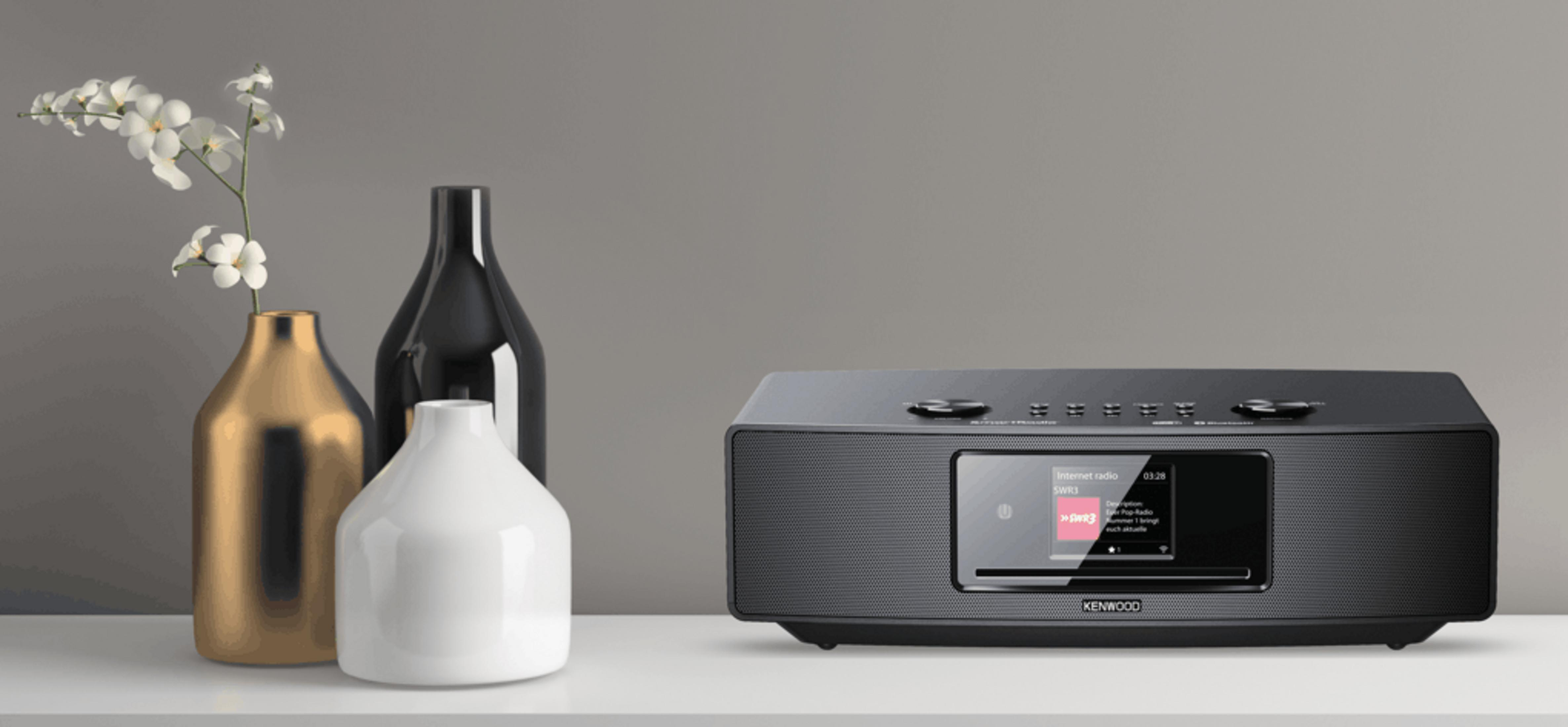 Een zwarte Kenwood internetradio met drie vazen op een plank.