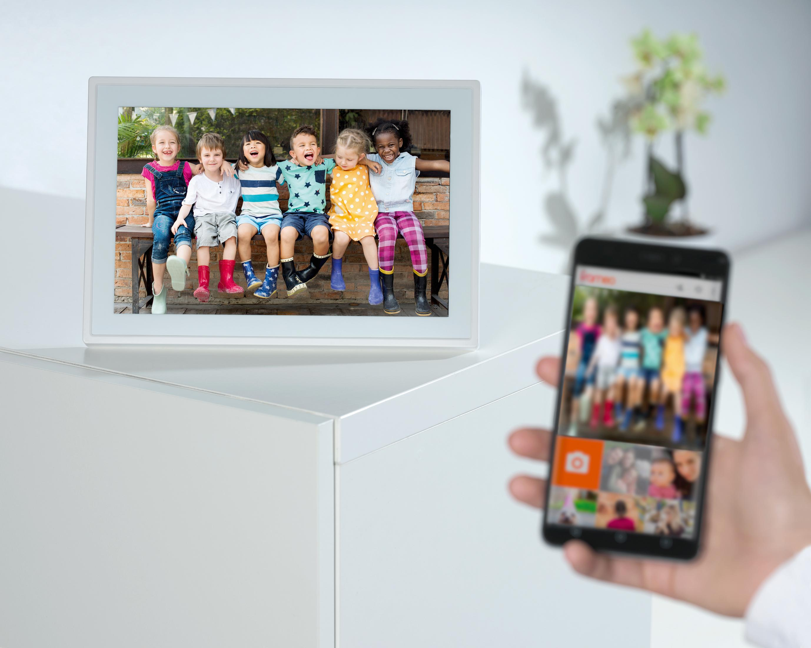 Sechs fröhliche Kinder sitzen auf einer Bank, ein Handy zeigt ihre Fotos.