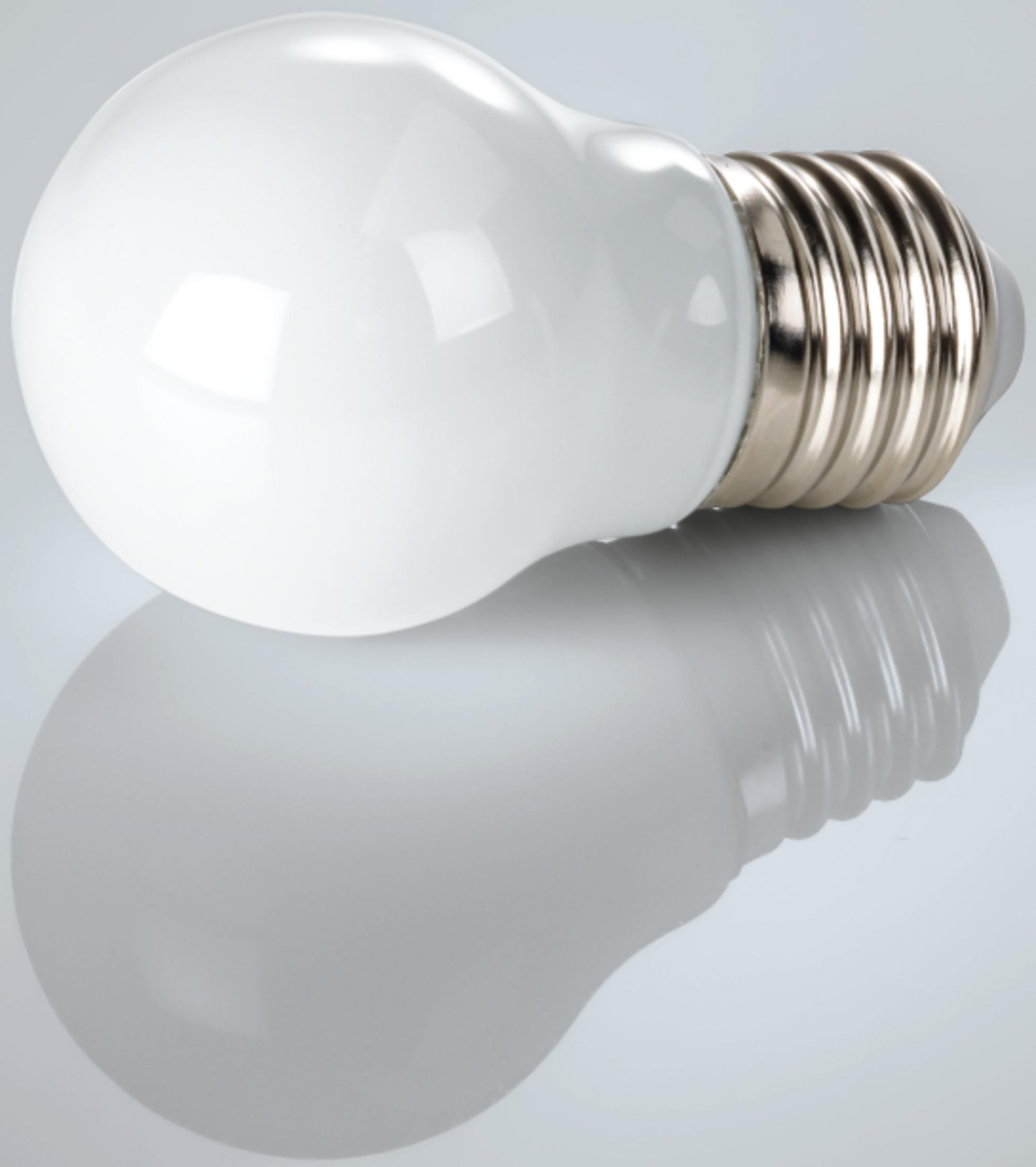 Biała żarówka leży na lustrzanej powierzchni.