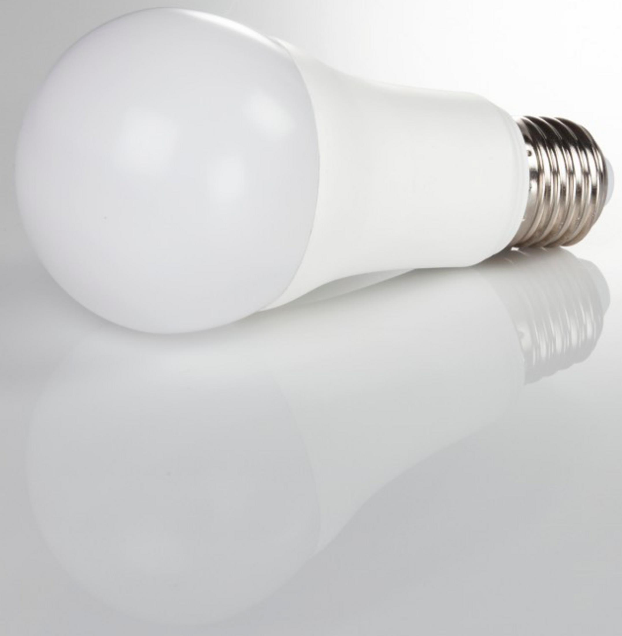 Eine weiße LED-Glühbirne liegt auf einer spiegelnden Oberfläche.