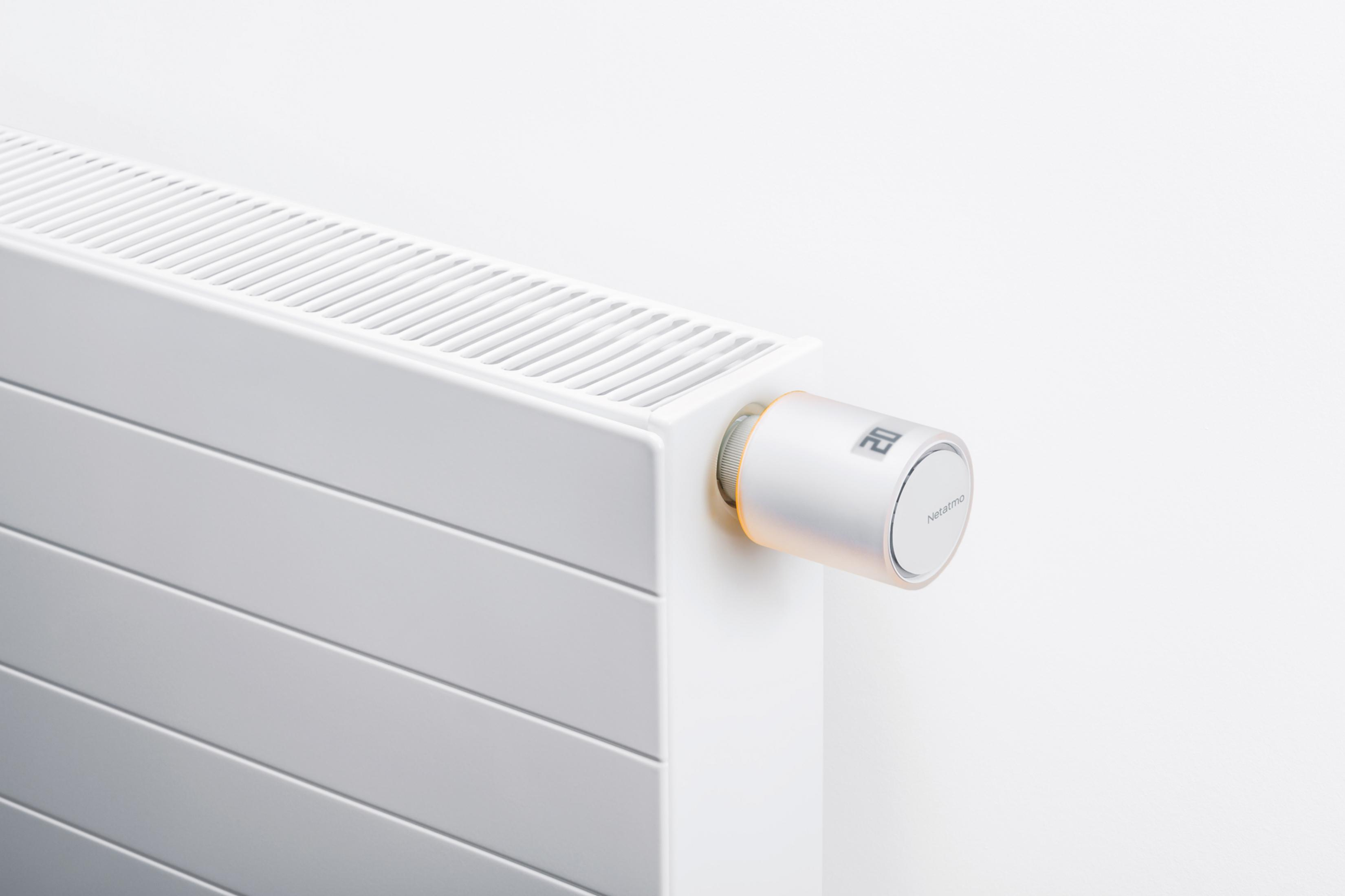 A white radiator with a silver thermostat displaying a digital temperature.