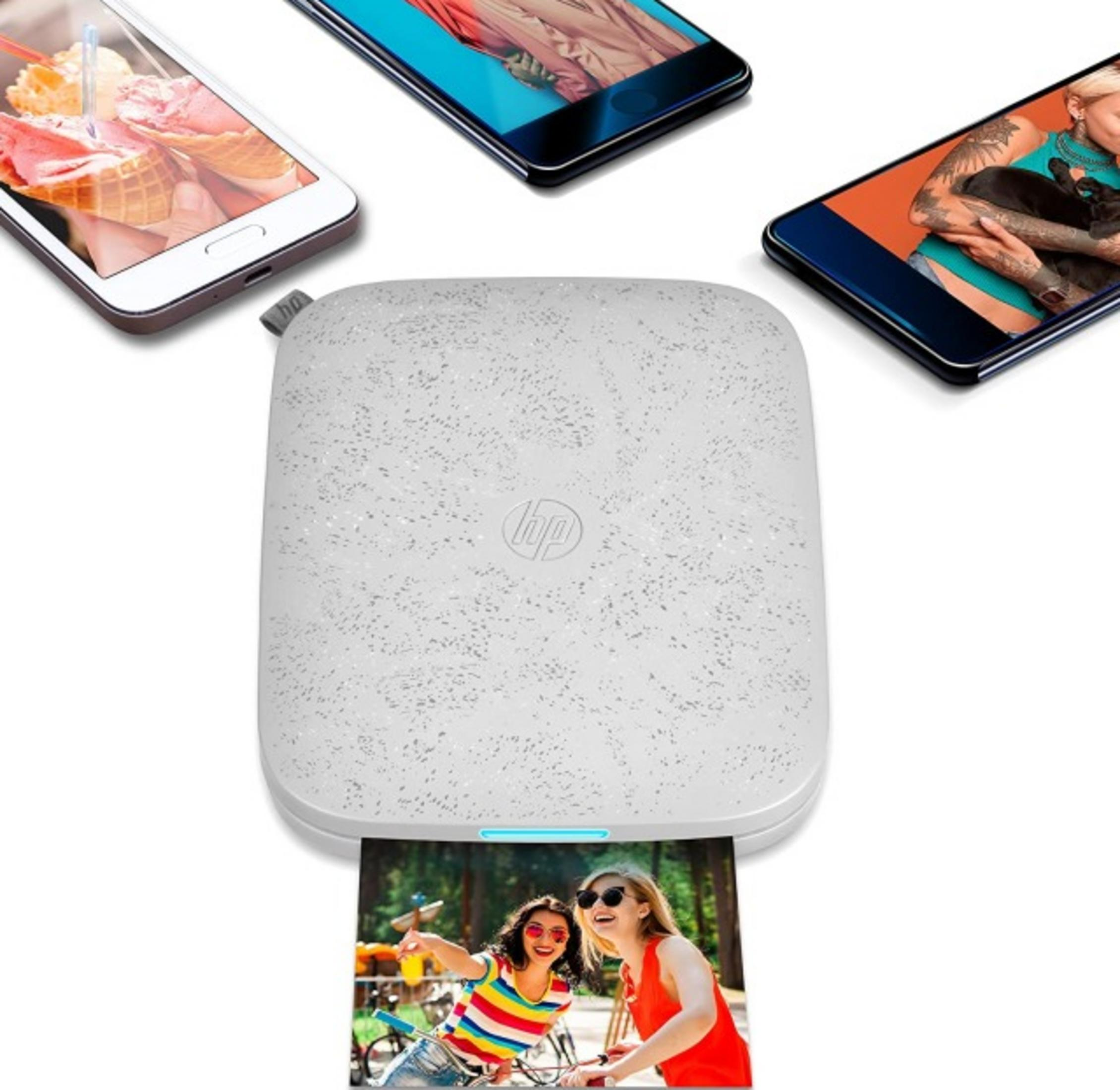 Biała drukarka drukuje zdjęcie dwóch kobiet na rowerach. Trzy smartfony w pobliżu.