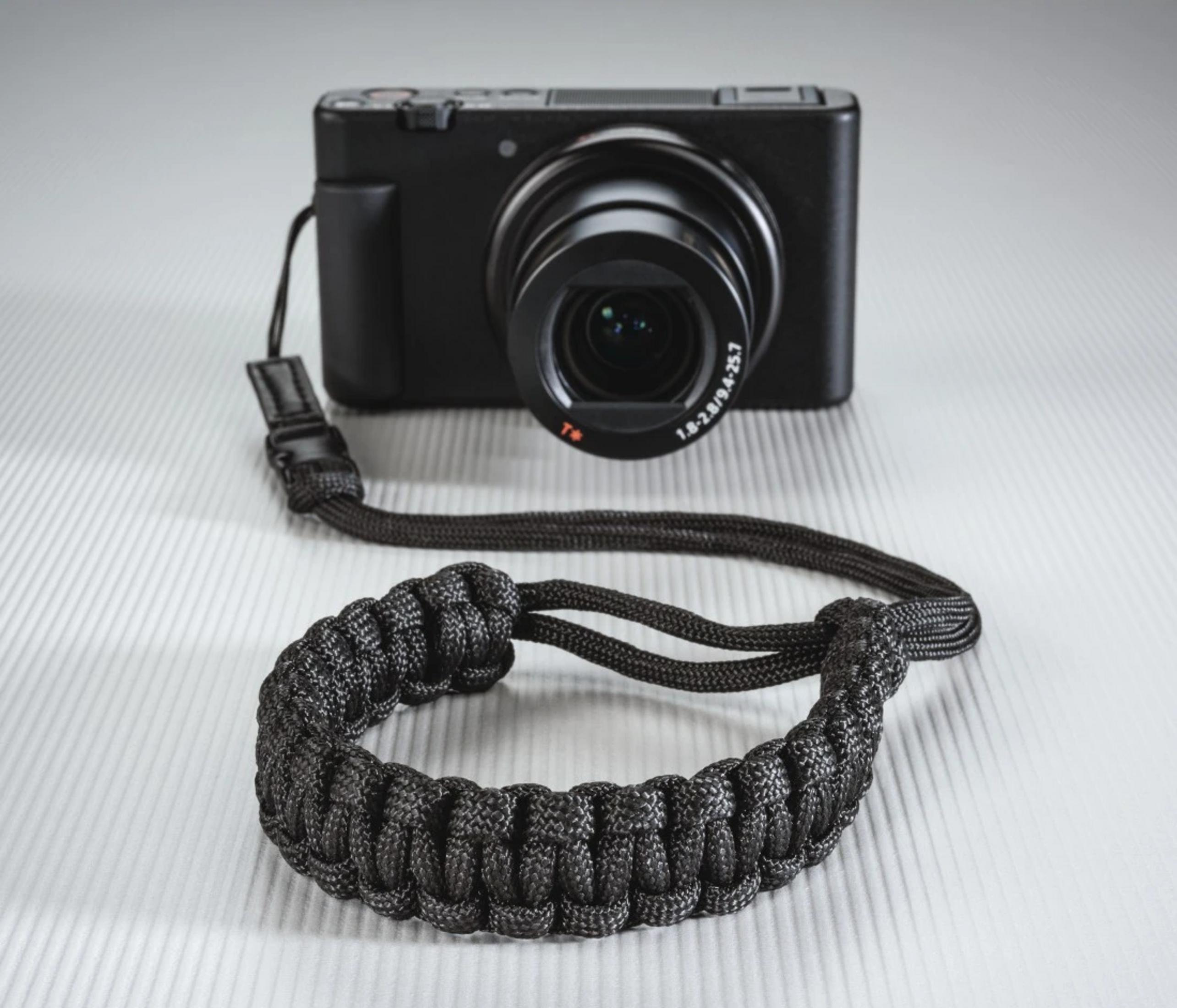 Czarny aparat z paskiem na nadgarstek z przodu, na prążkowanej powierzchni.