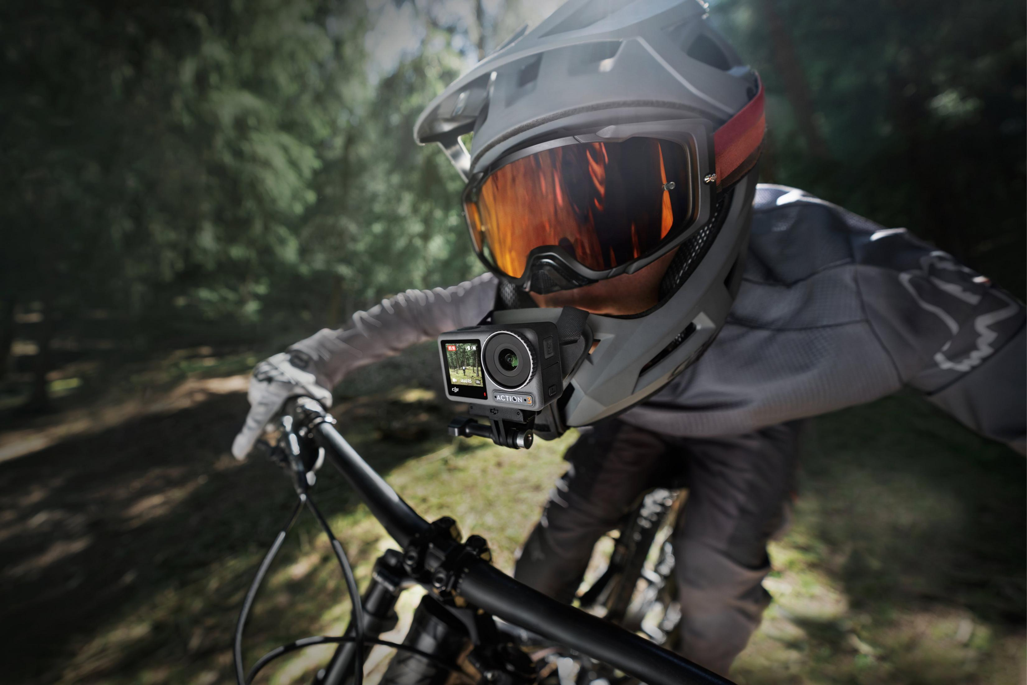 Mountain biker con casco e action cam pedala attraverso un bosco.
