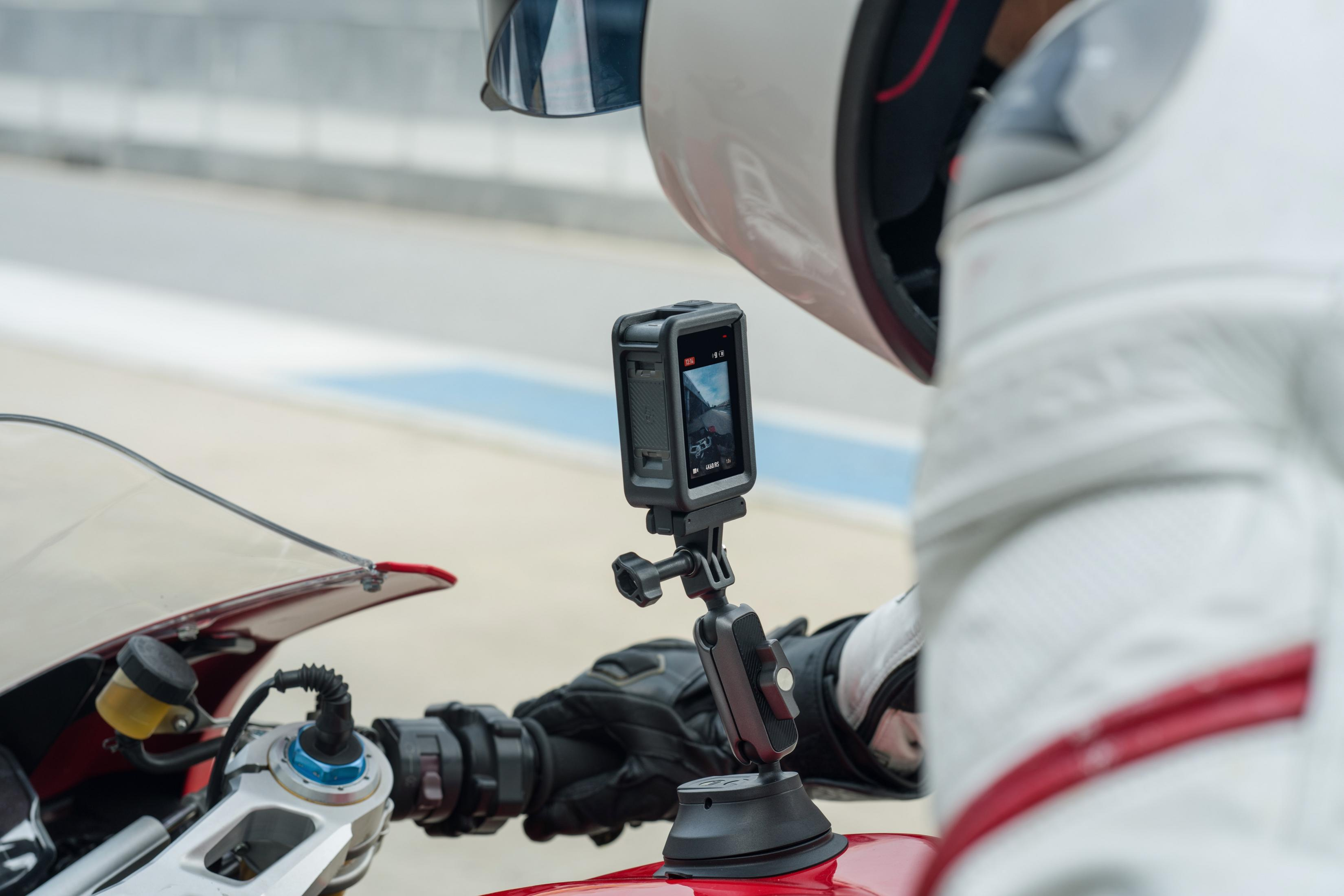 Een motorrijder met helm filmt met een actiecamera op zijn motor.