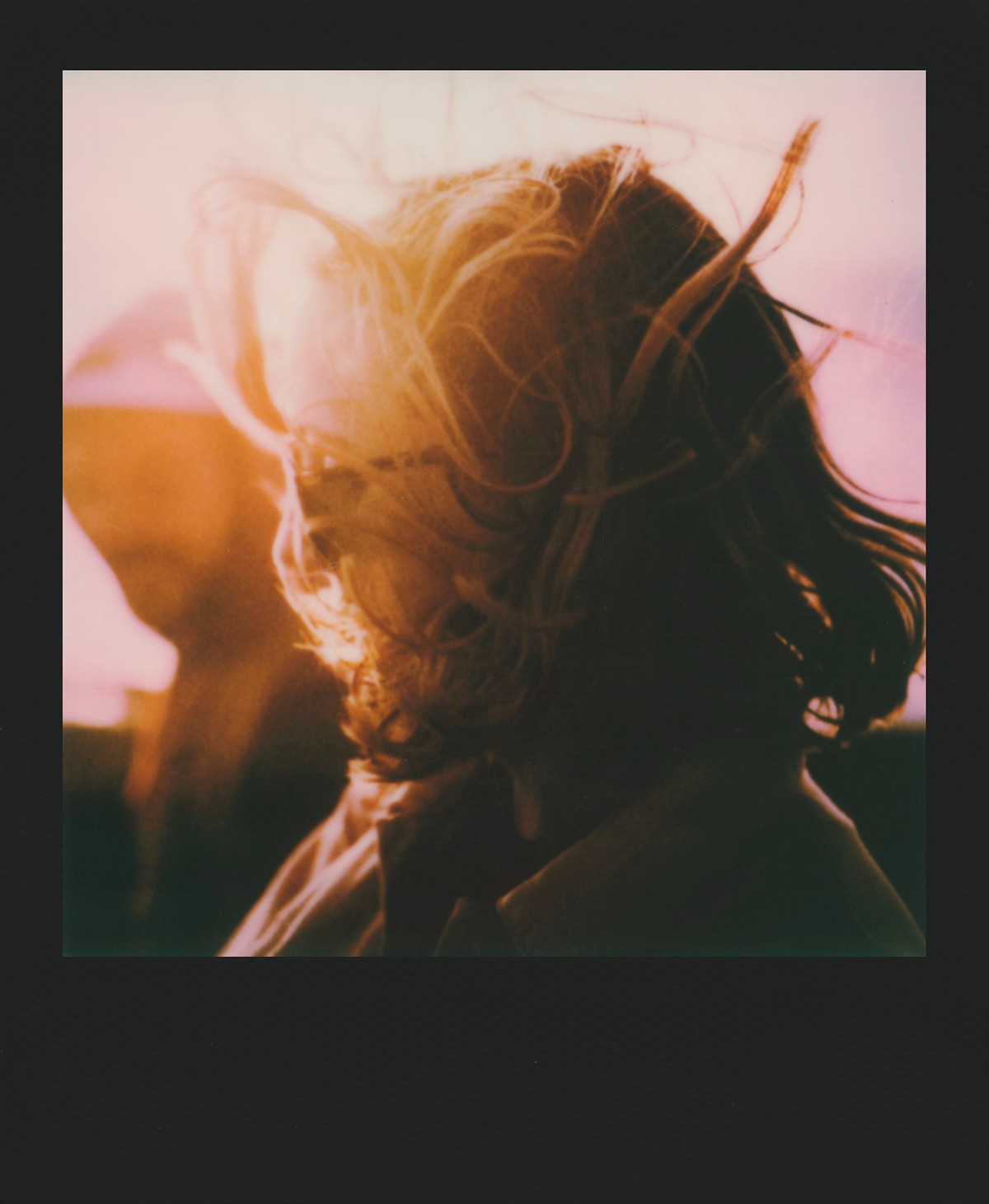 Zbliżenie na osobę z rozwianymi włosami w ciepłym świetle.