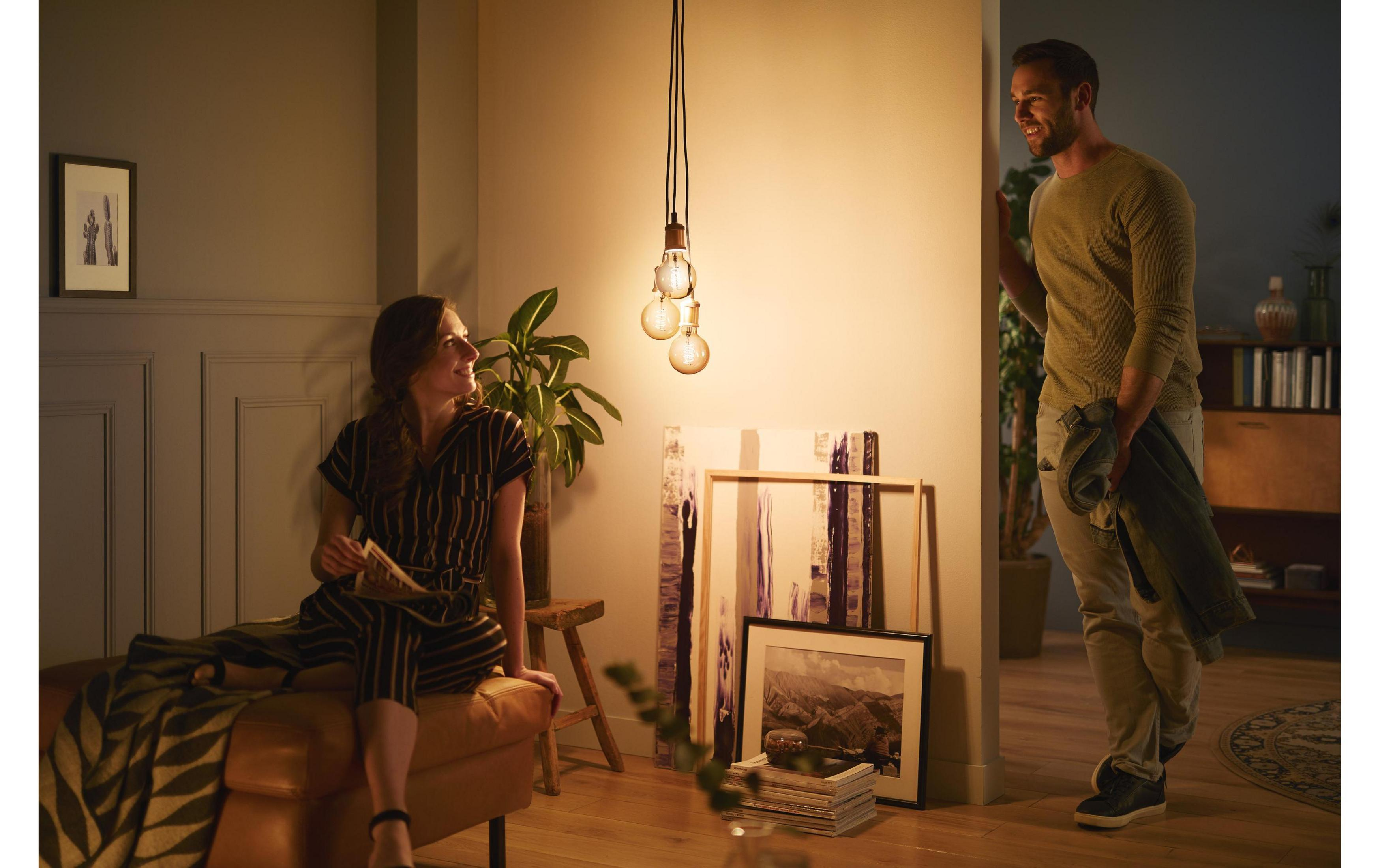 Man and woman in a cozy living room with pendant lights and art.