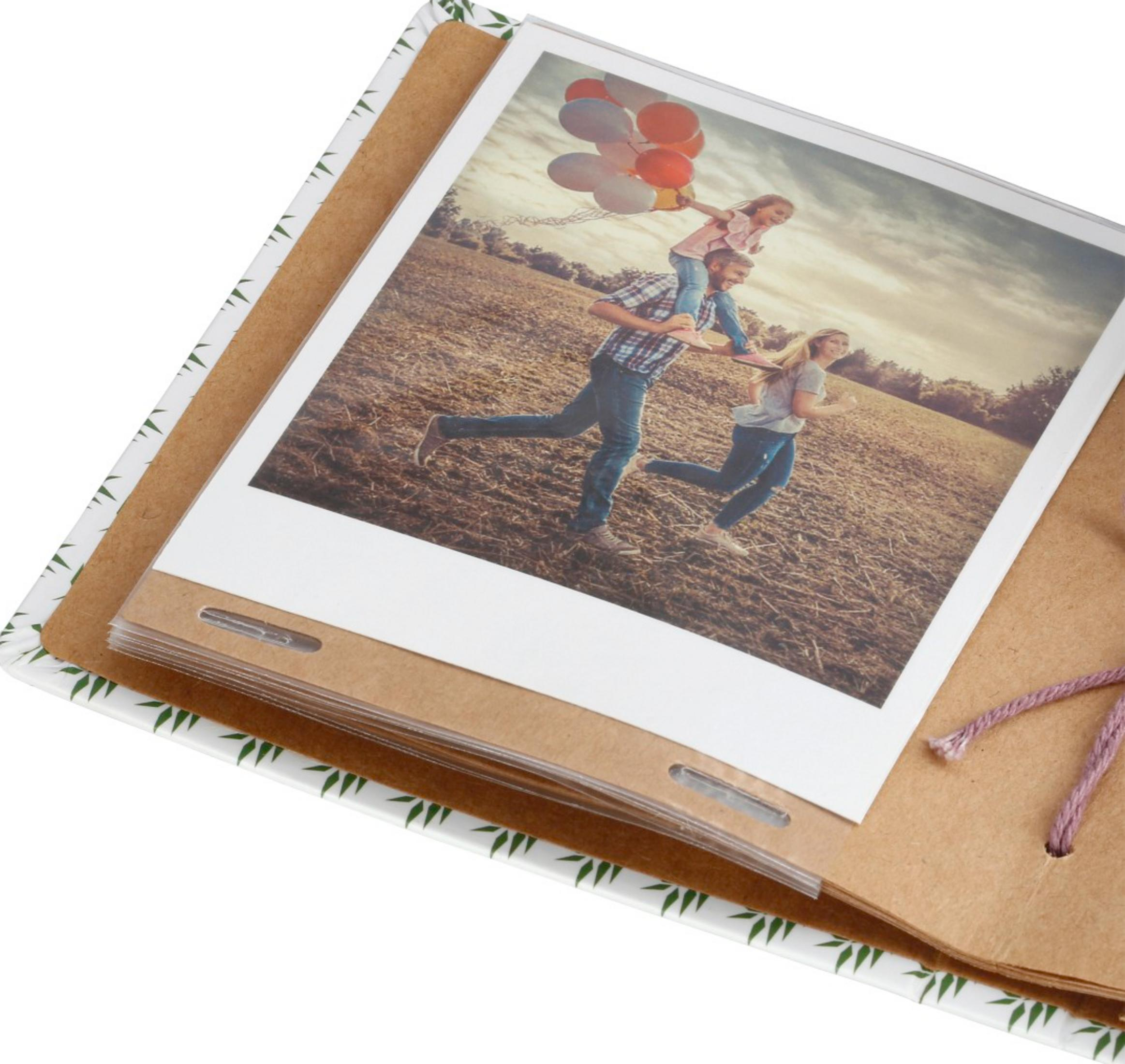 Rodzina biegnie w polu z balonami, ojciec niesie dziecko na ramionach.