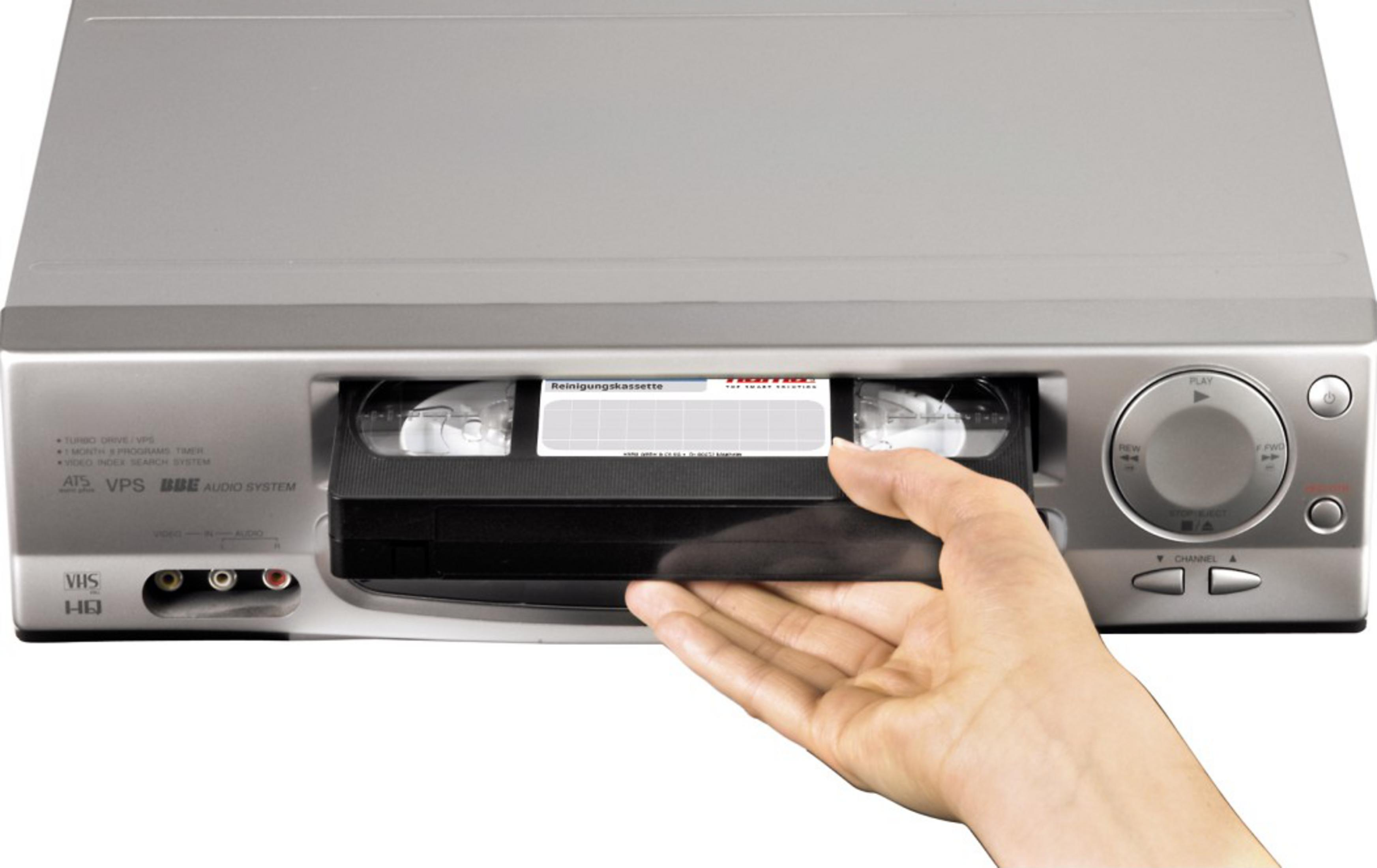 Eine Hand schiebt eine Reinigungskassette in ein silbernes VHS-Gerät.
