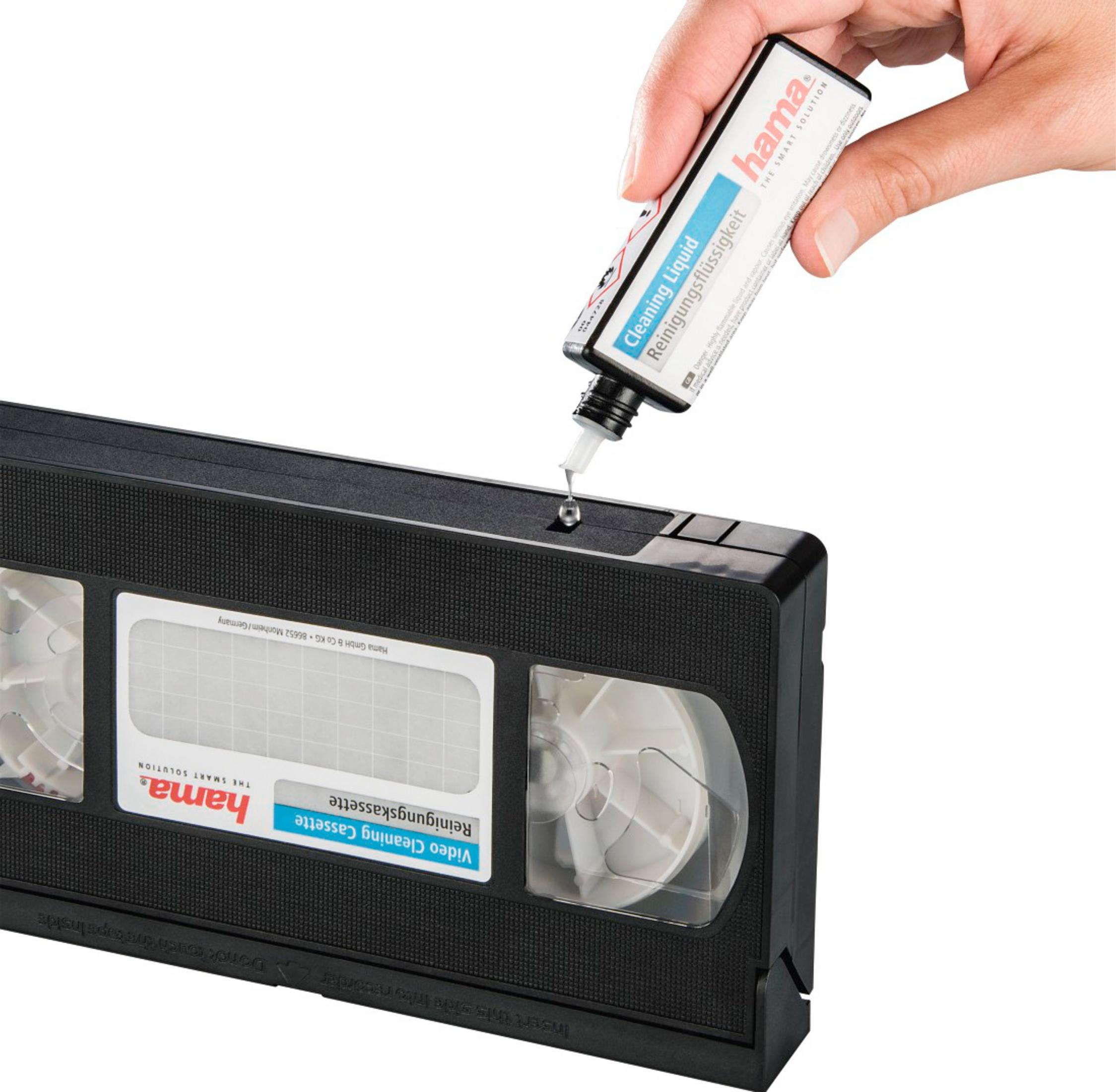 Eine Hand gibt Reinigungsflüssigkeit aus einer Flasche auf eine VHS-Reinigungskassette.