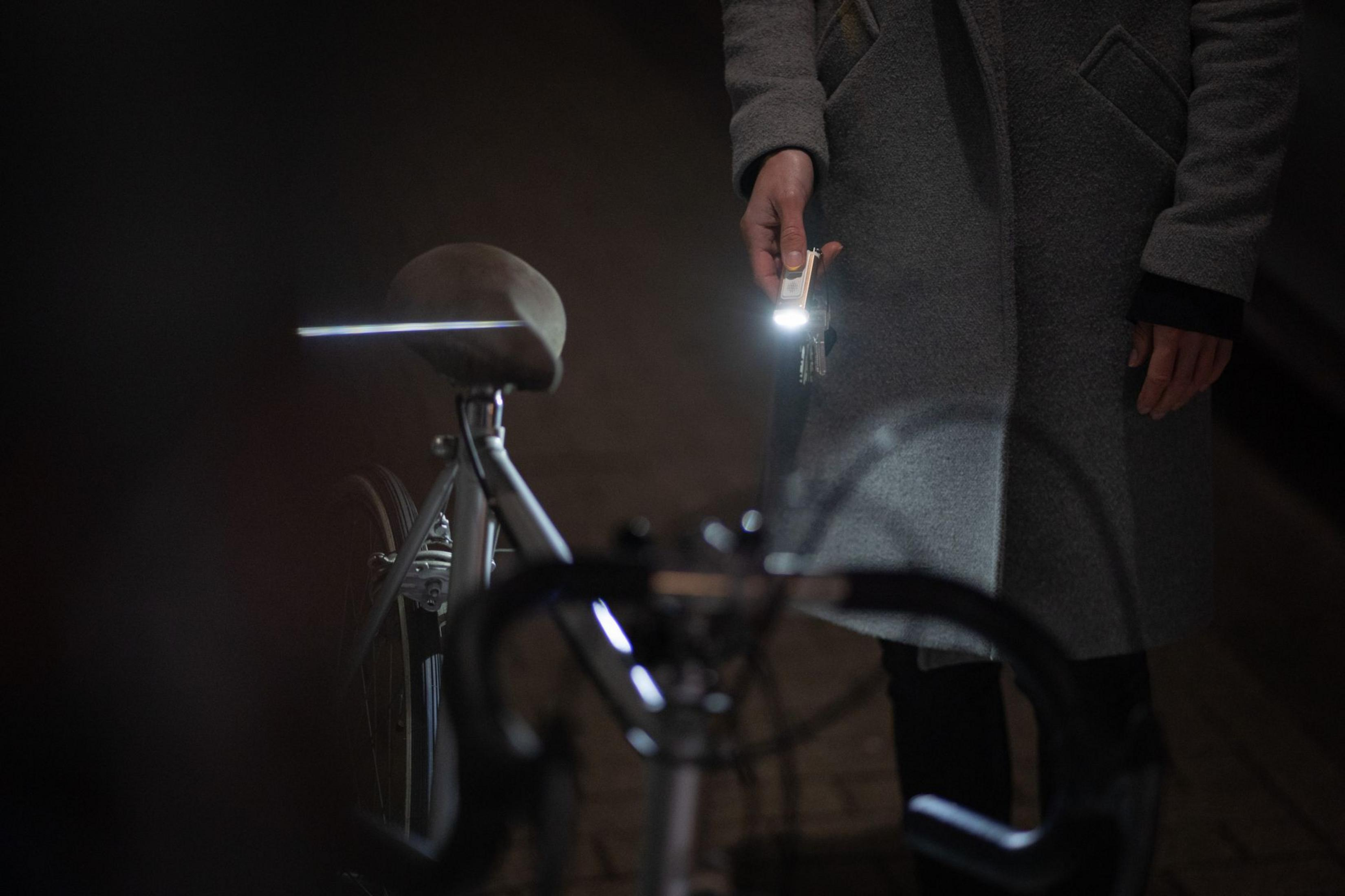 Osoba z latarką i rowerem w ciemności.