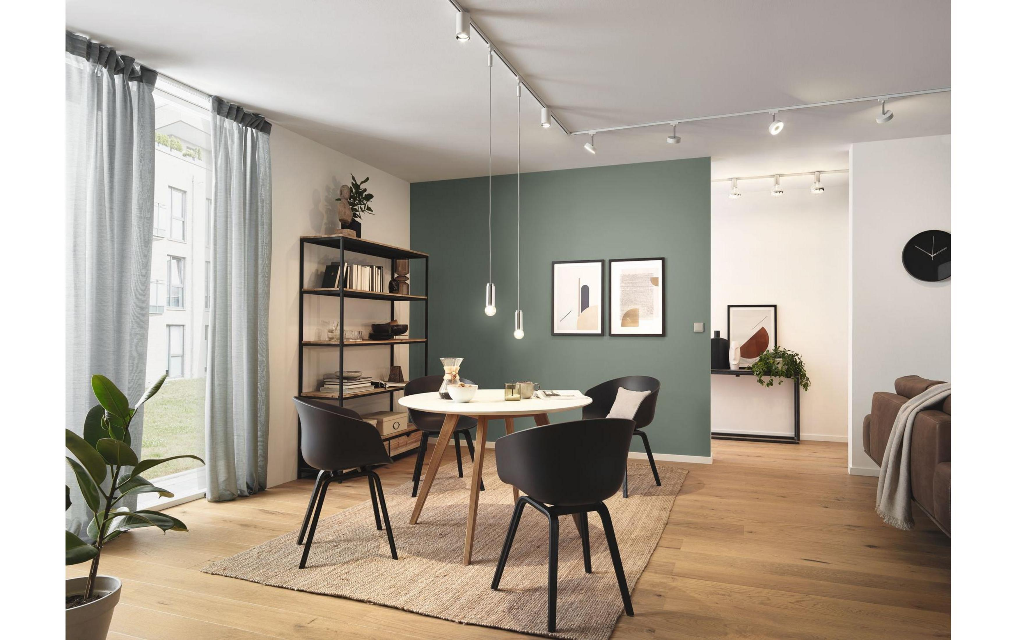 Esszimmer mit rundem Tisch, schwarzen Stühlen, Regal und Wandkunst.