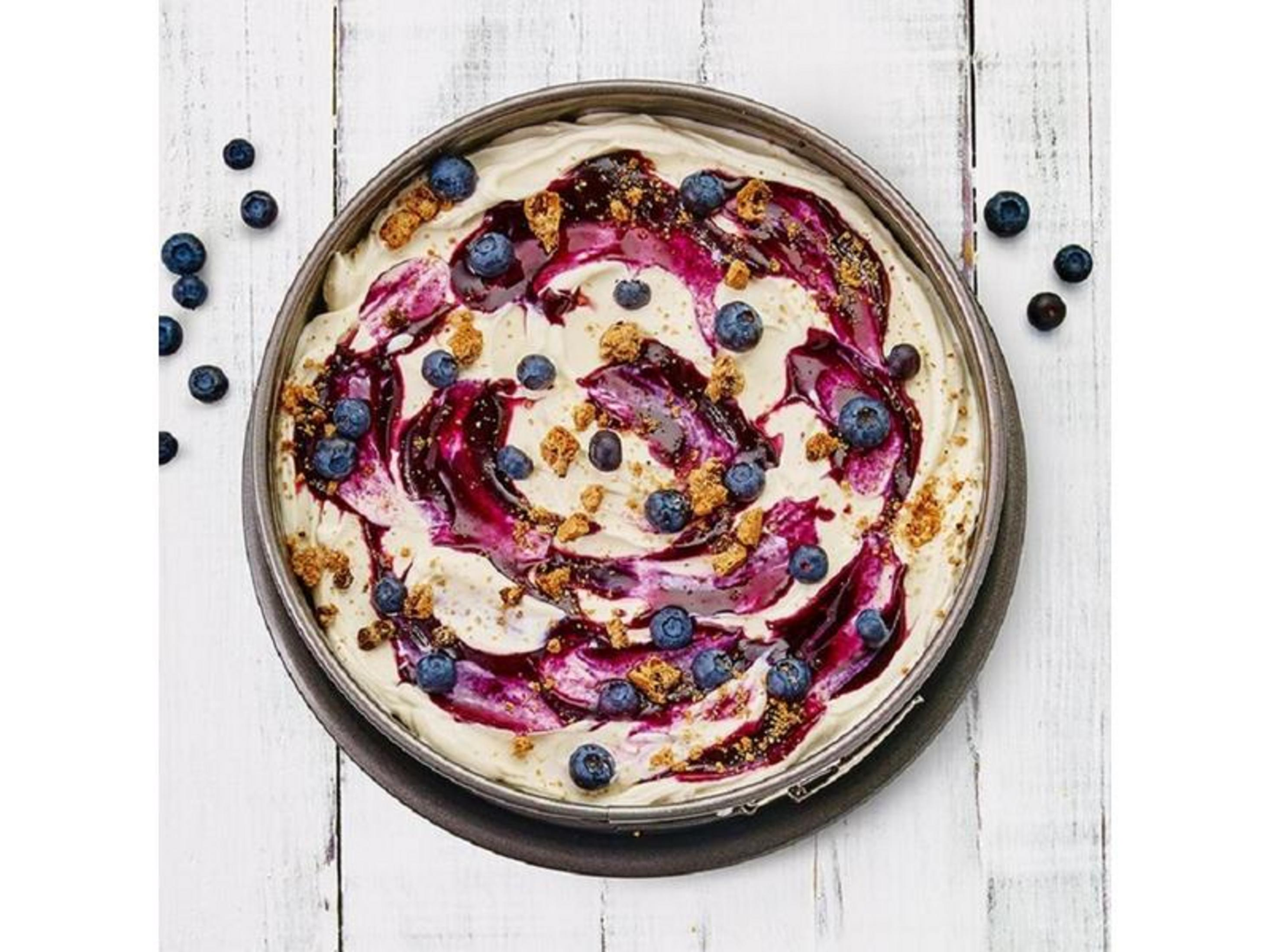 Creme-Torte mit Blaubeeren und Blaubeersauce, auf weißem Holztisch.
