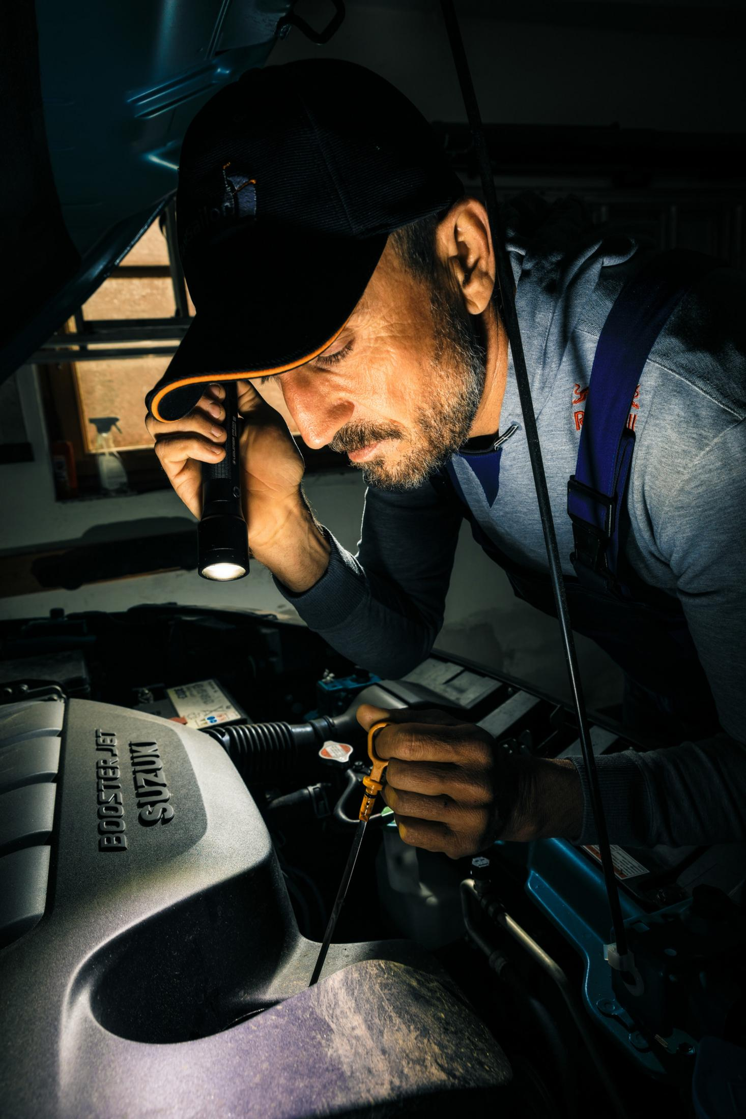 Mechanik sprawdza latarką silnik samochodu.