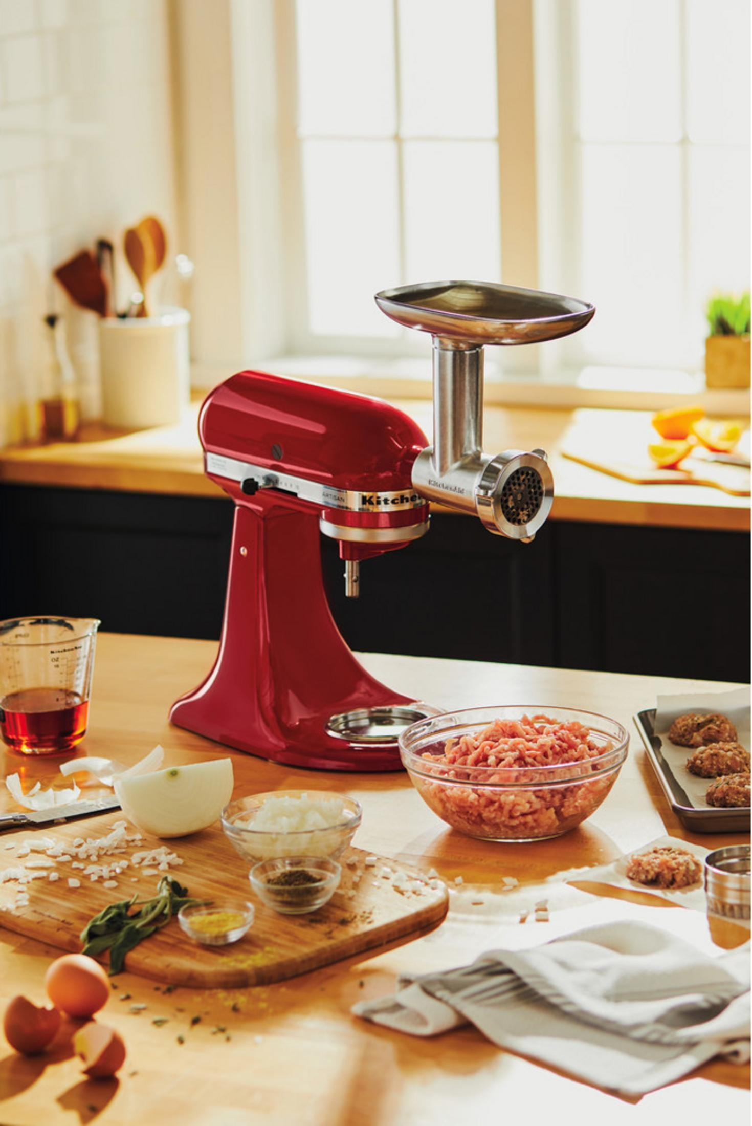 Rode standmixer met vleesmolenopzetstuk, kom met gehakt, uien, eieren.