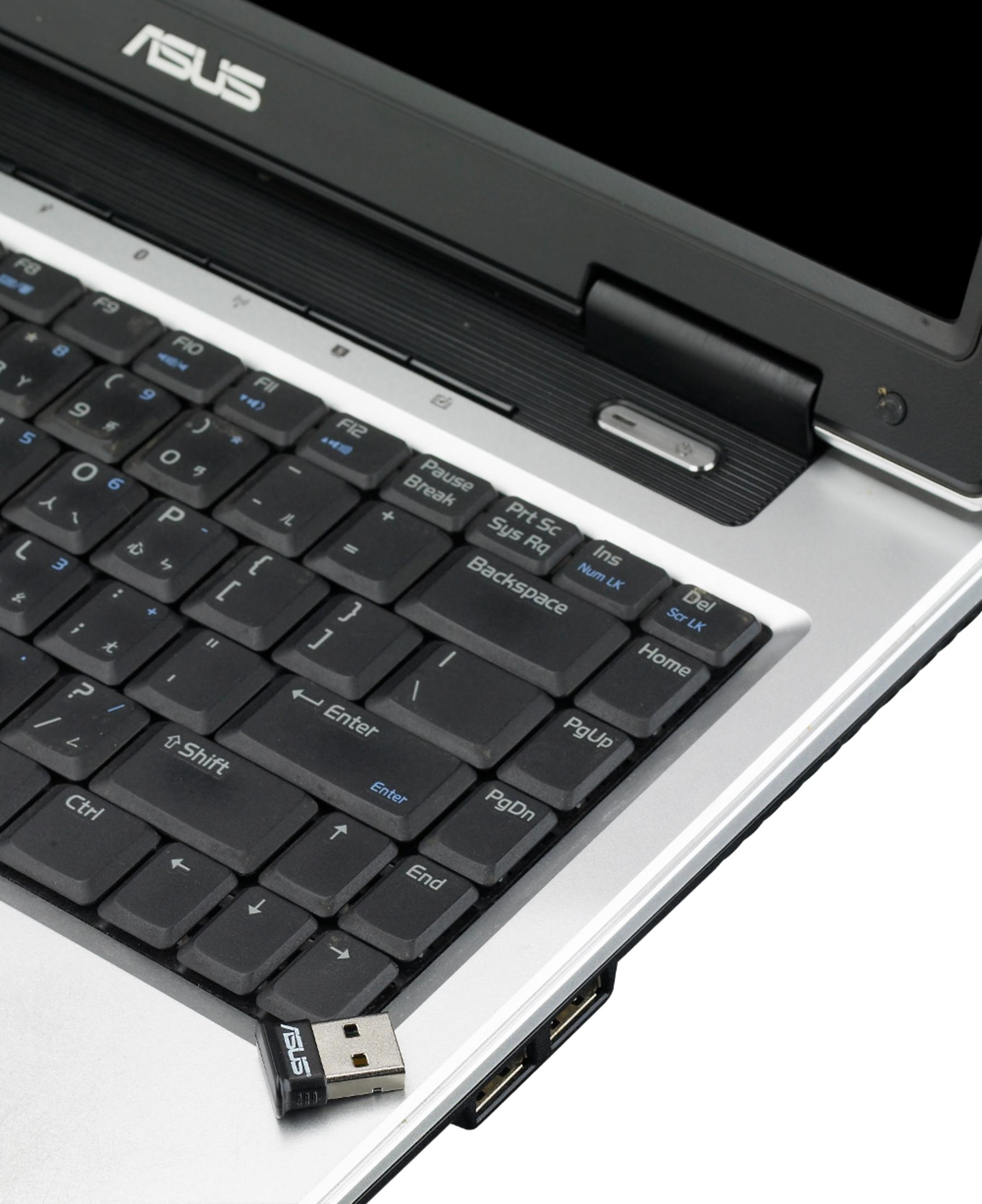 Un portátil ASUS con un pequeño dongle USB en primer plano.