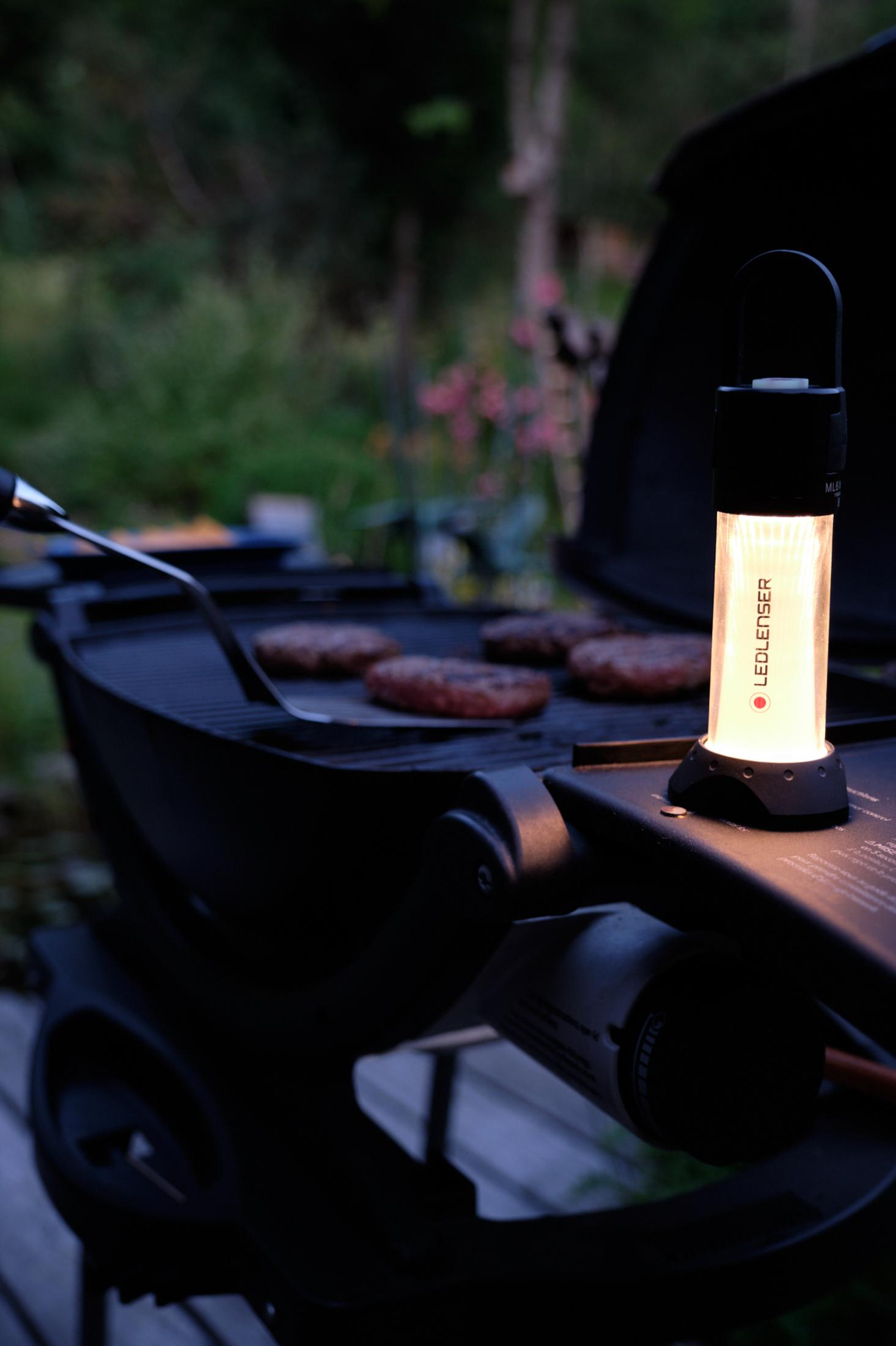 Burger auf einem Grill, beleuchtet von einer Laterne