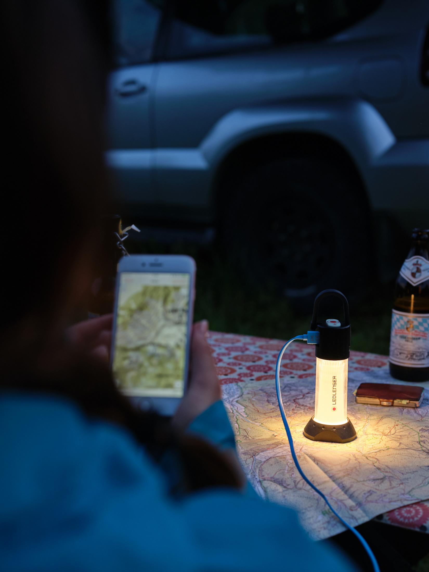 Eine Person hält ein Smartphone mit Karte. Eine Lampe leuchtet auf einer Karte.
