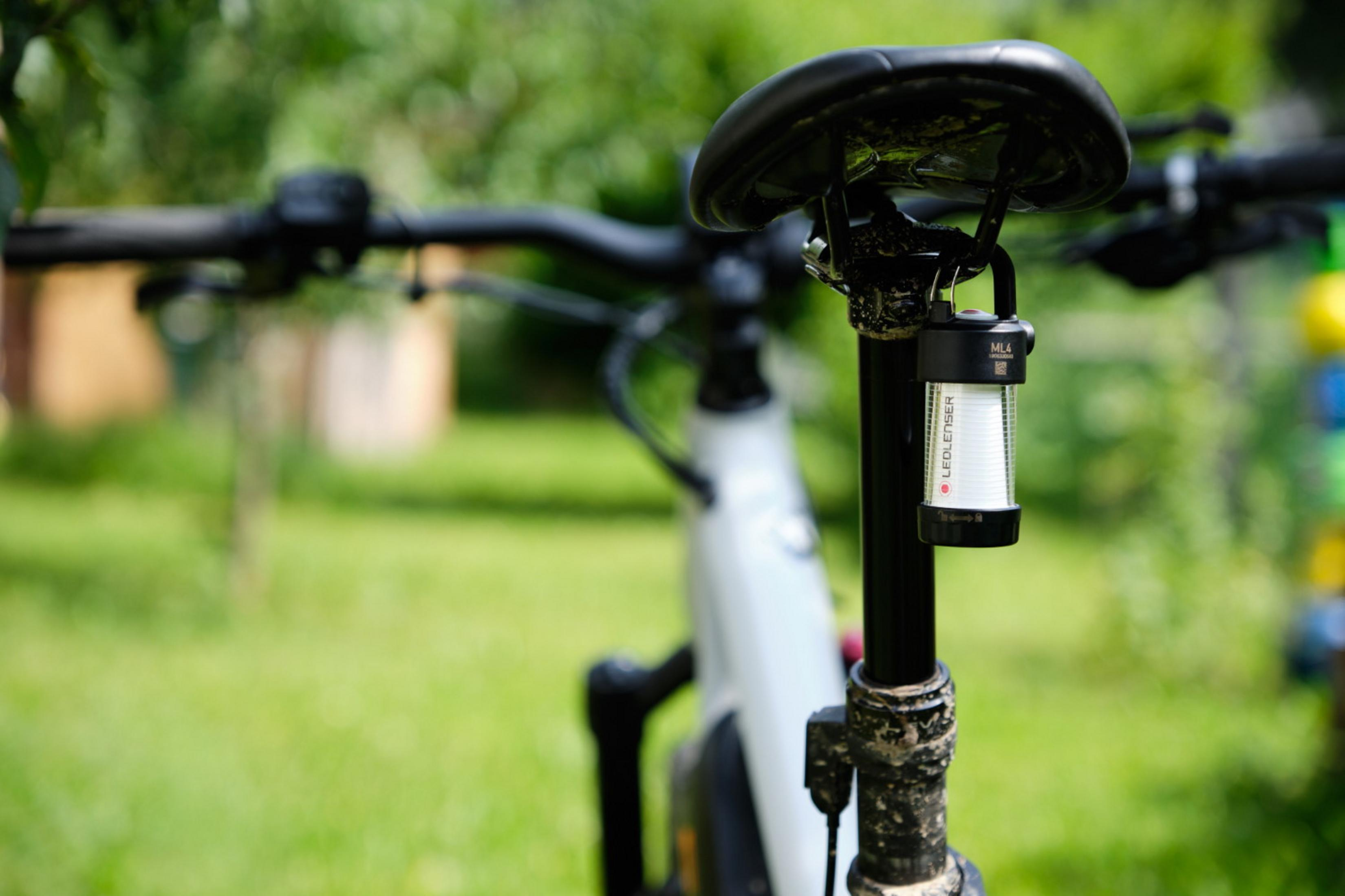 Una piccola lanterna LED Ledlenser ML4 nera è attaccata al reggisella di una mountain bike.