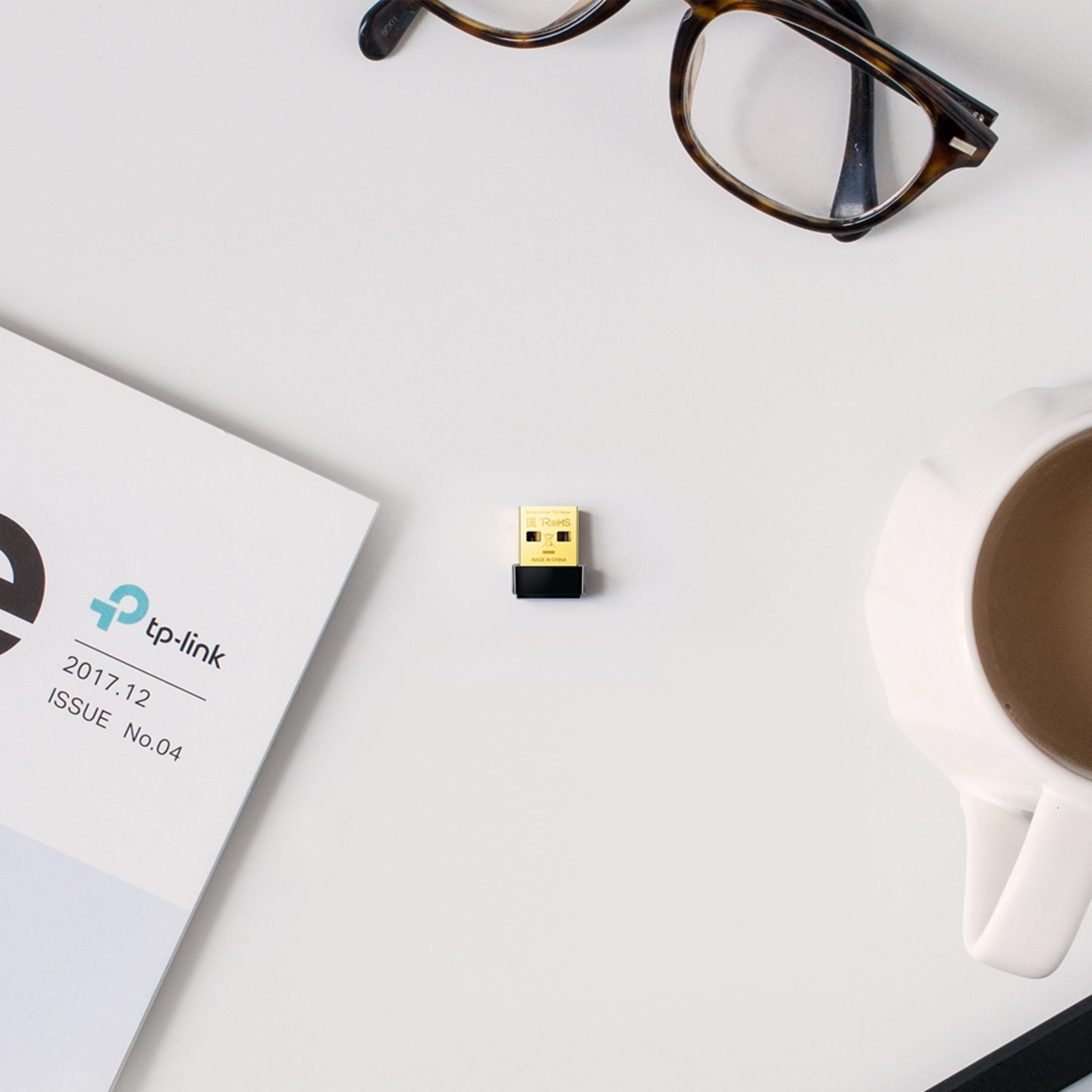 Ein kleiner goldener USB-Stick liegt auf einer weißen Oberfläche neben einer Brille, einer Zeitschrift und einer Kaffeetasse.
