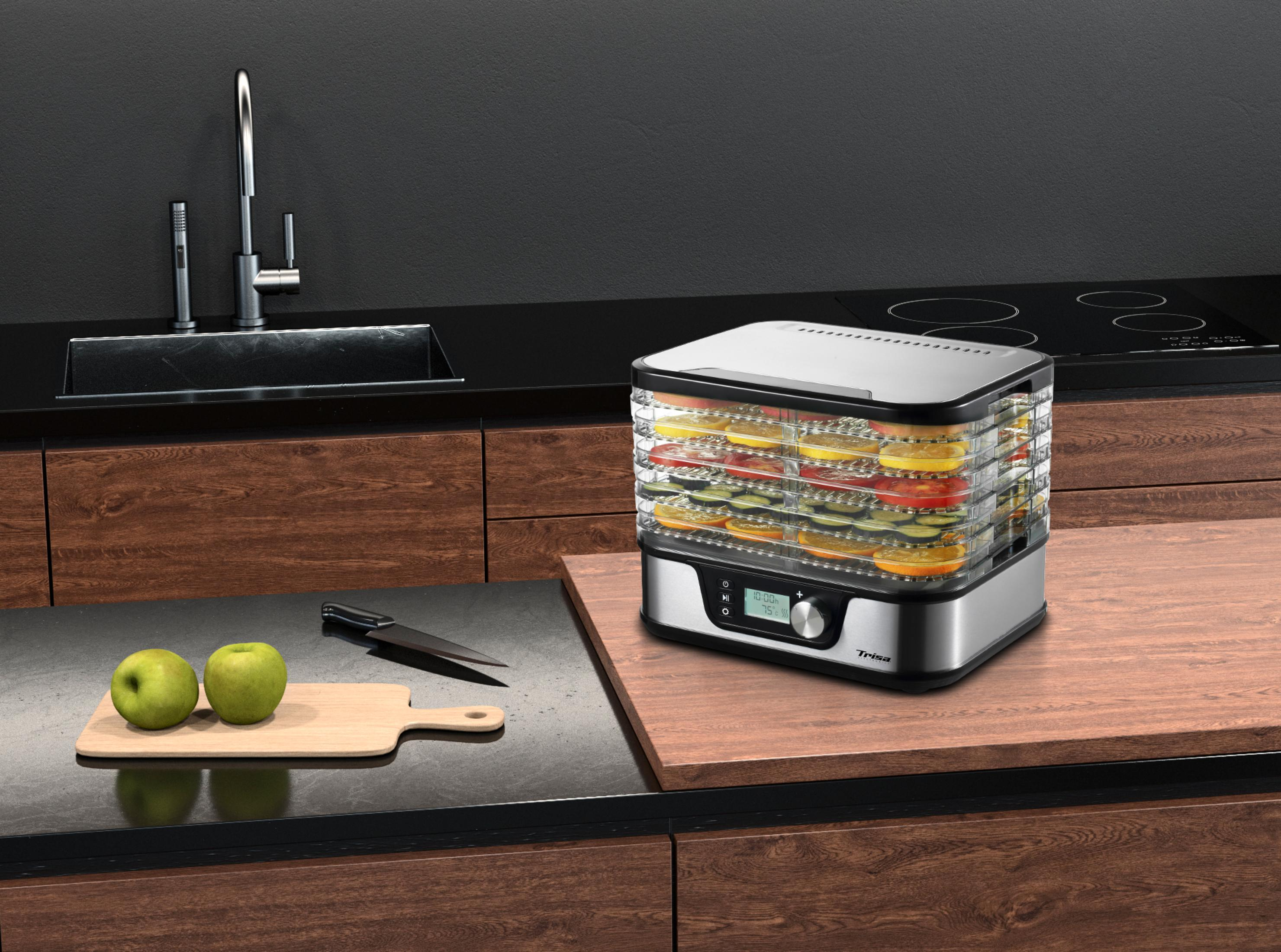 Un déshydrateur alimentaire avec fruits et légumes sur un plan de travail en bois près d'un évier.