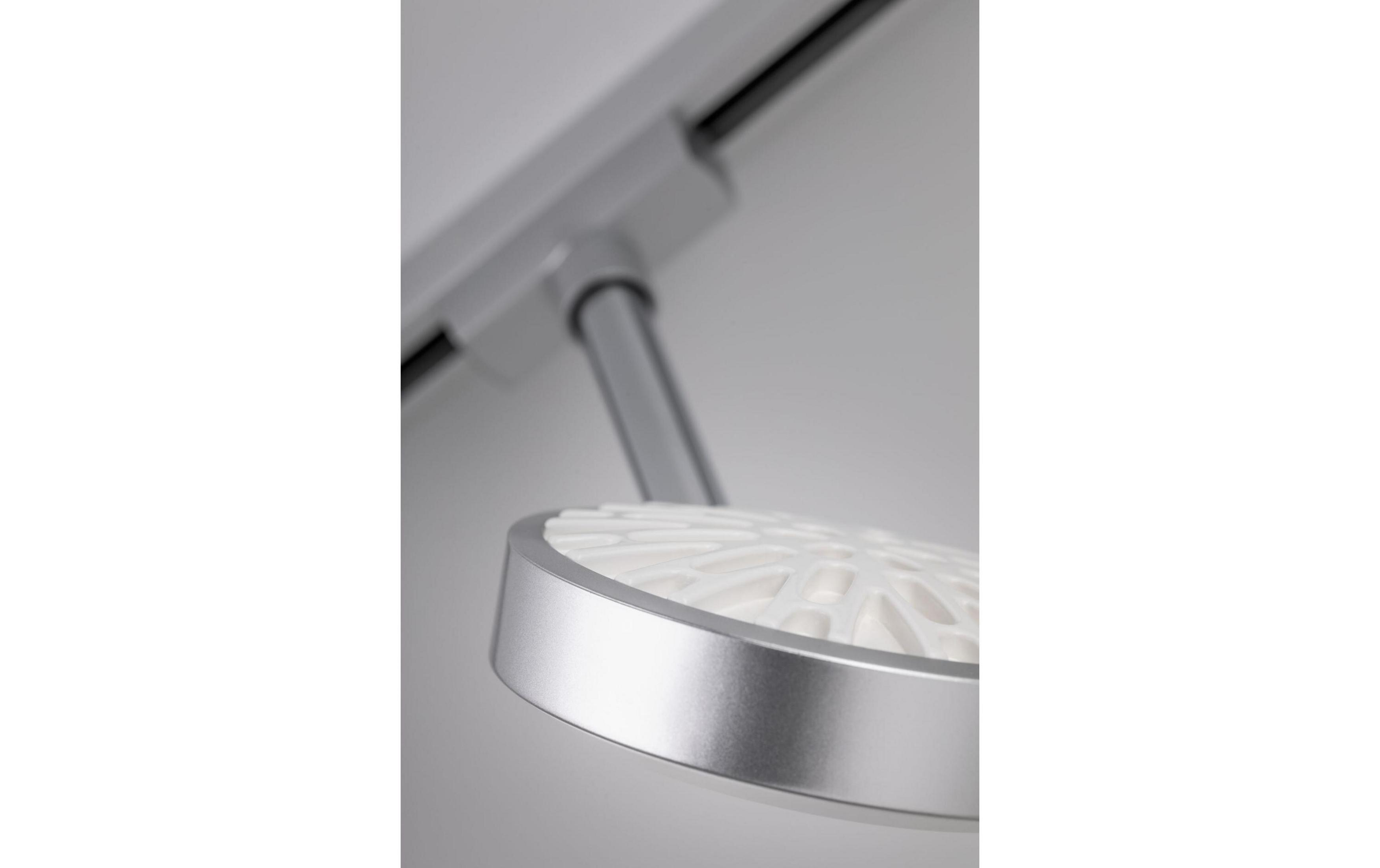 Nahaufnahme einer silbernen Lampe mit weißem, durchbrochenem Lampenschirm auf einer Schiene.