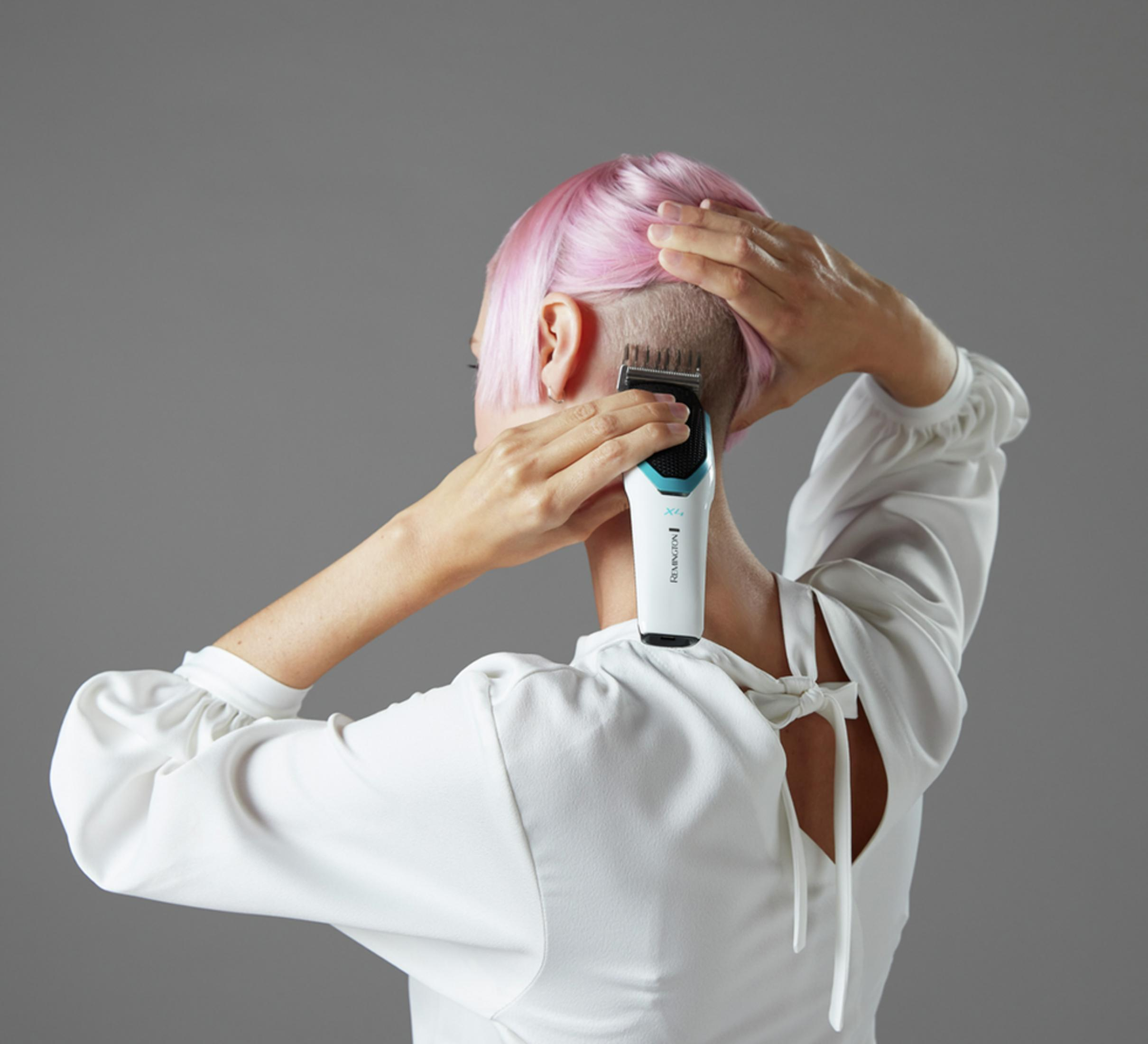 Persona con capelli rosa si taglia la nuca con un trimmer Remington.