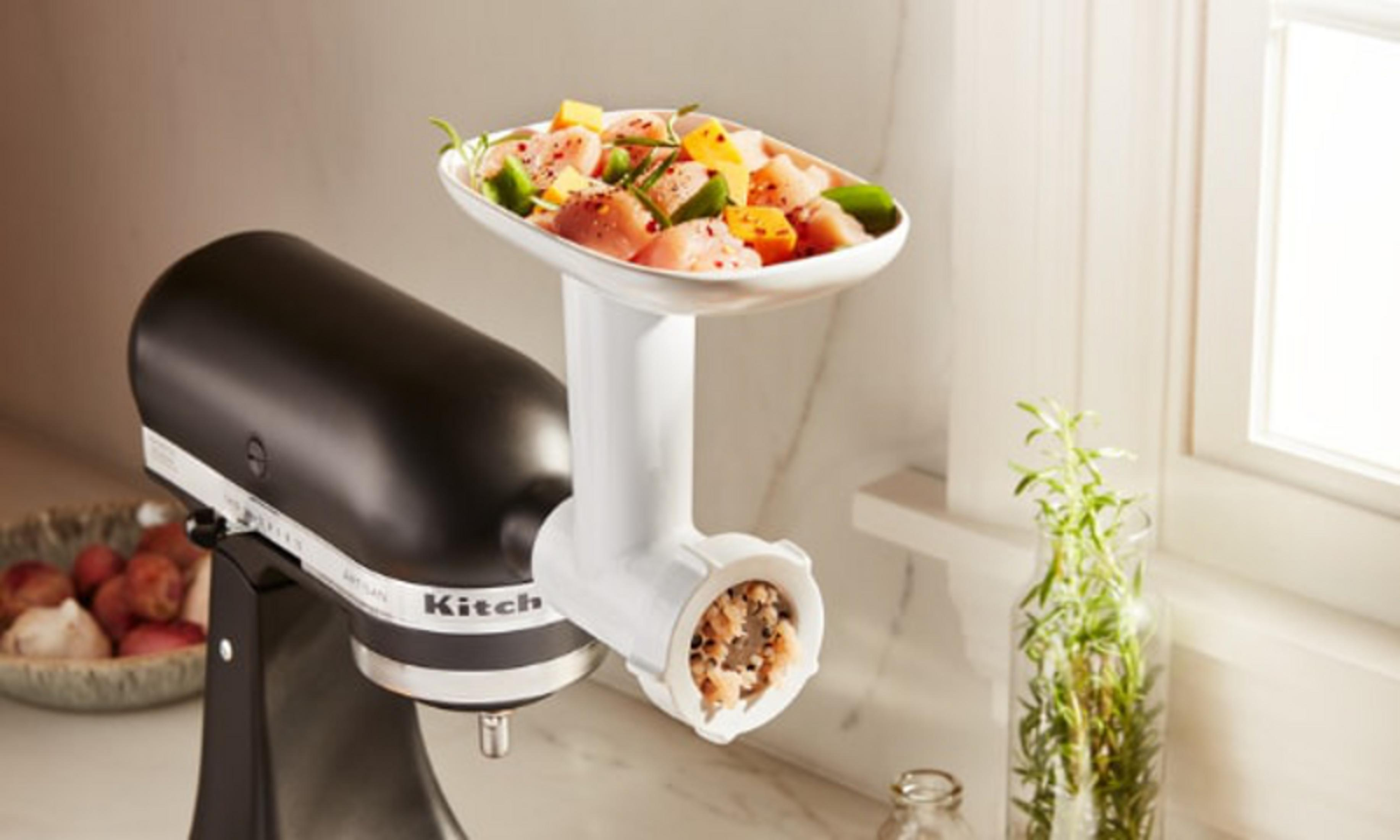Un accessorio per tritacarne su una KitchenAid con pollo crudo e spezie.