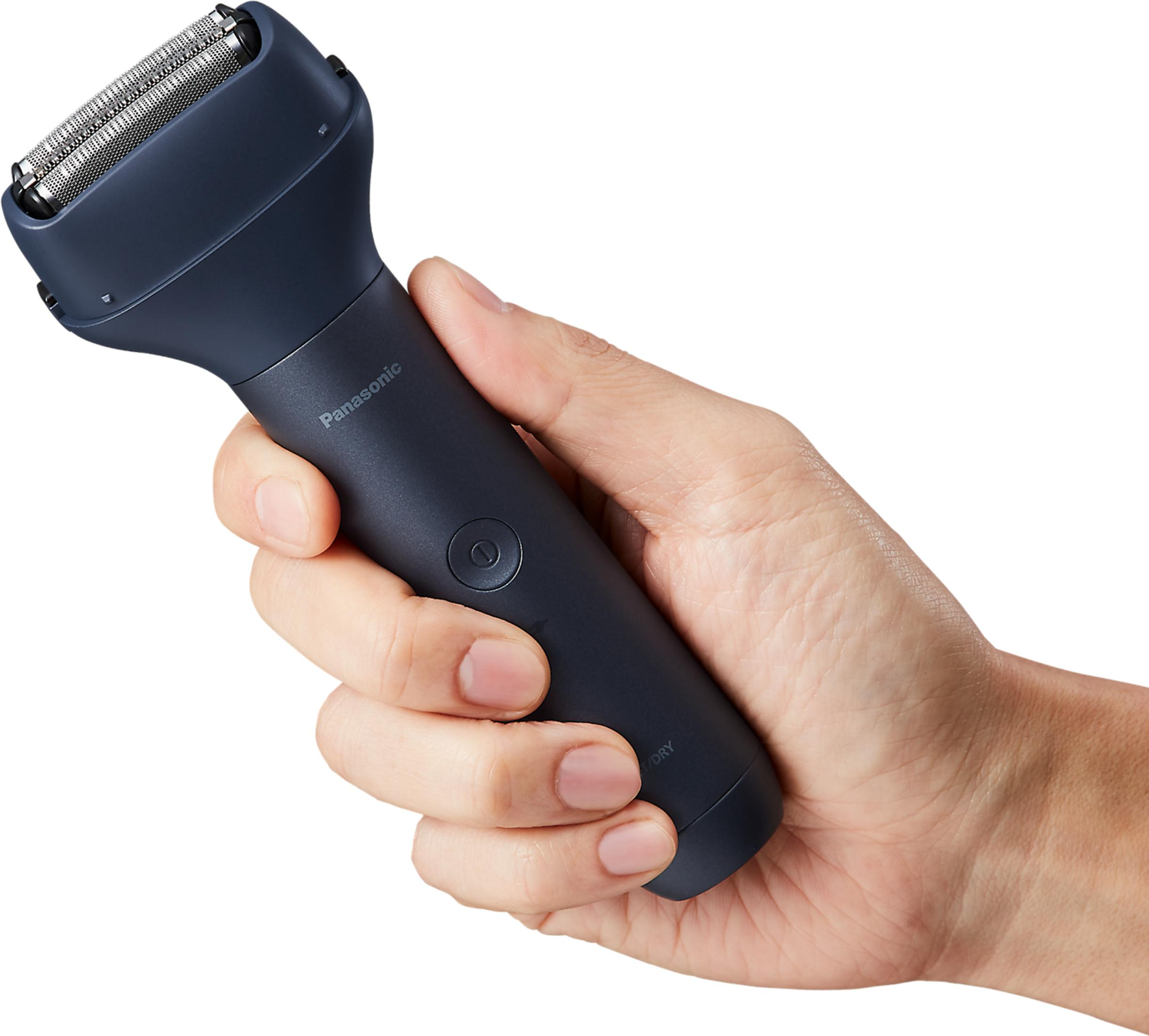 Dłoń trzyma ciemną golarkę Panasonic ze srebrnymi ostrzami.