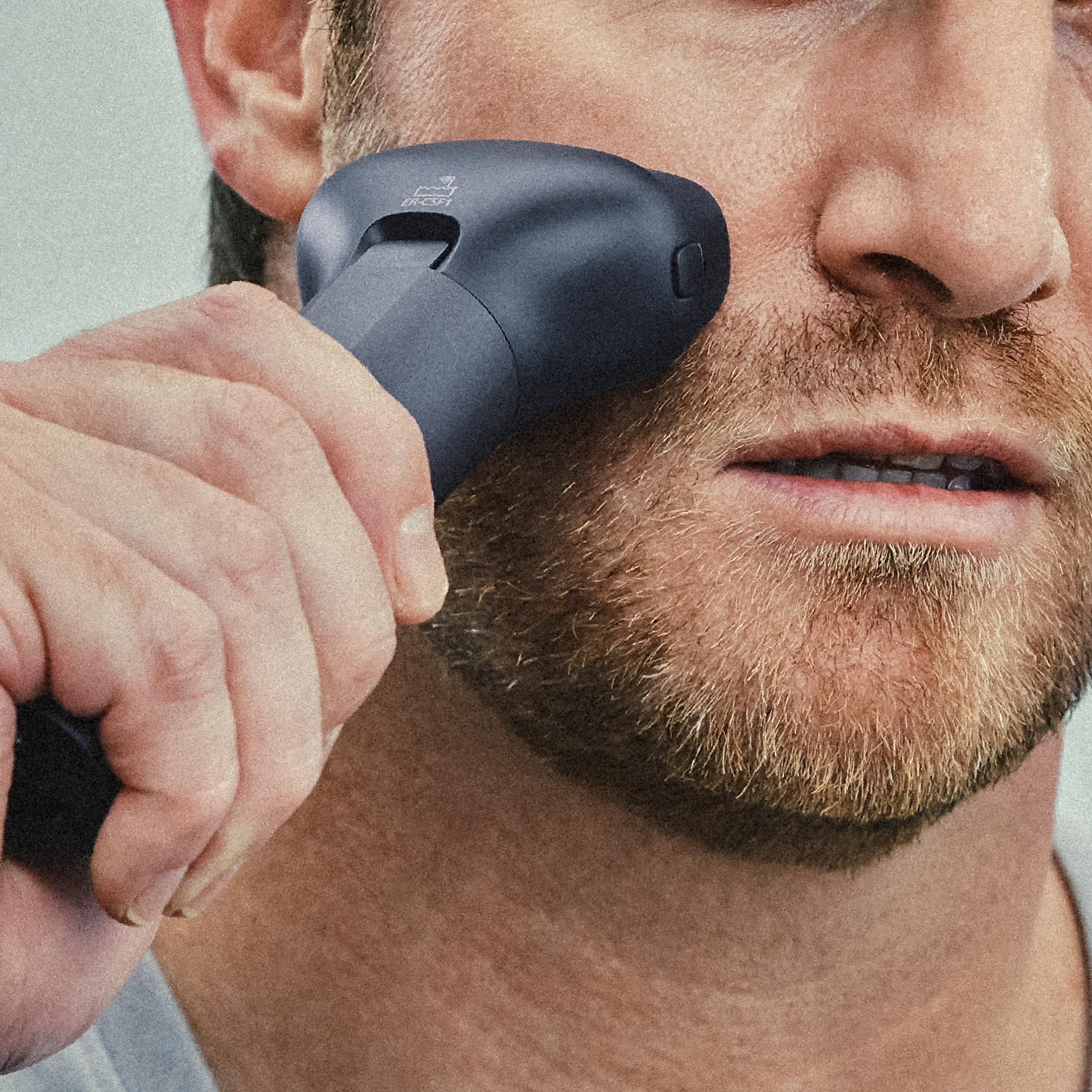 Mężczyzna używa ciemnego urządzenia elektronicznego na twarzy.