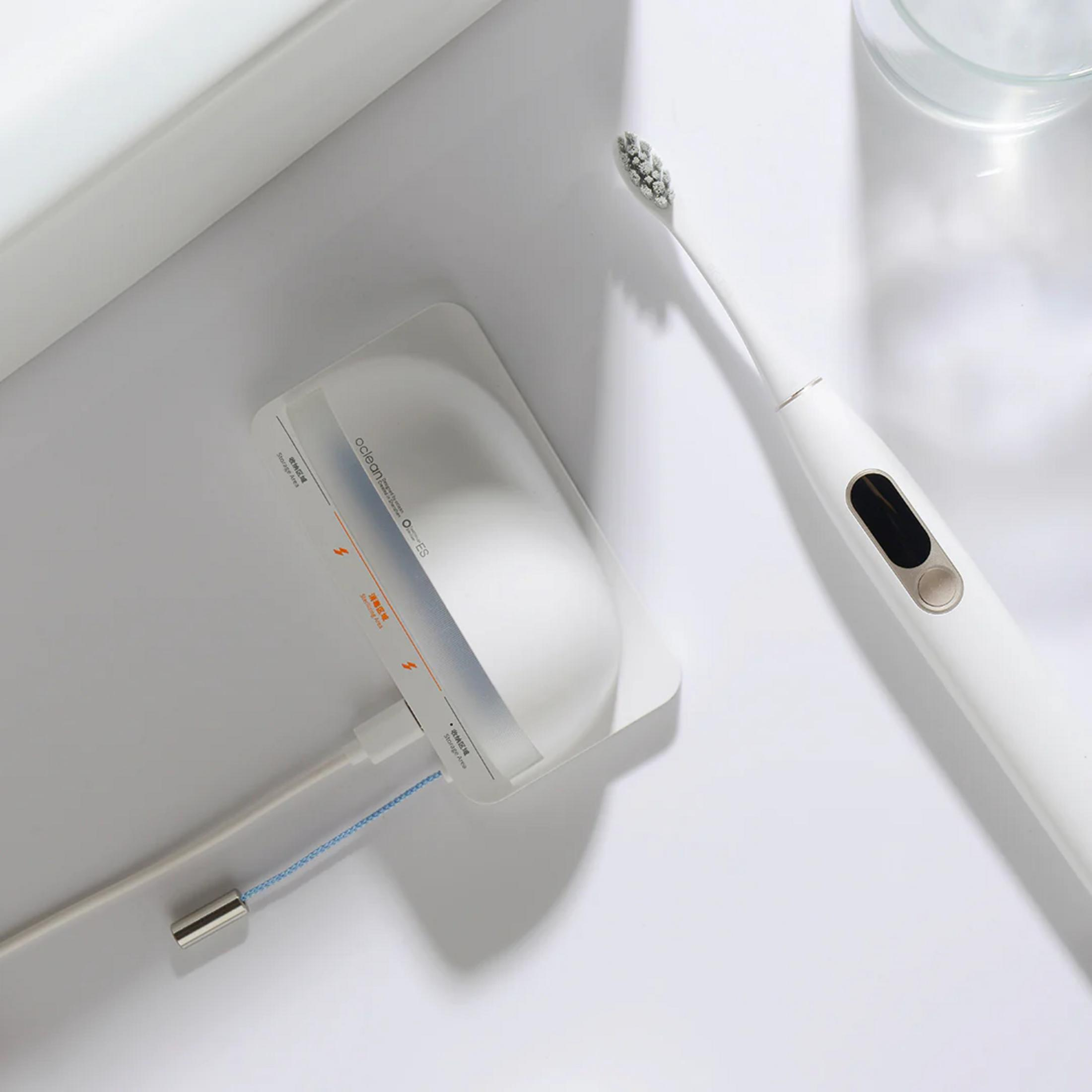 Un juego de cepillo de dientes eléctrico blanco con base de carga y vaso.