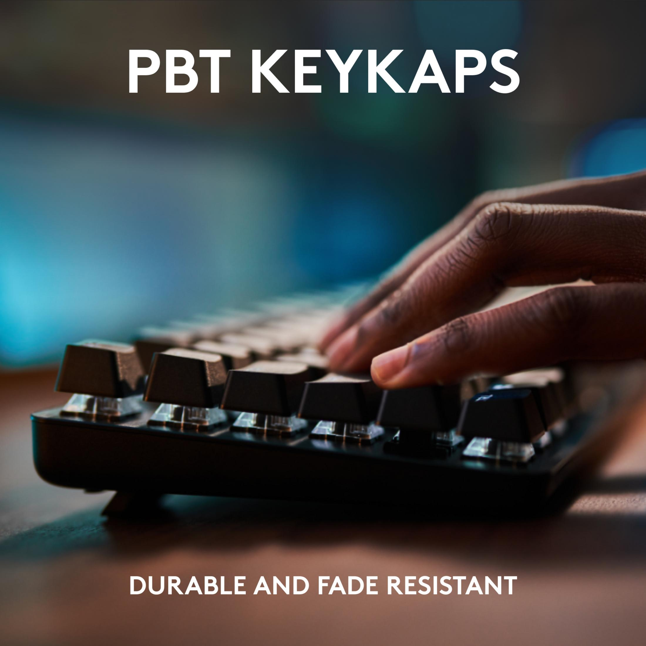 Czarne klawisze PBT na klawiaturze z piszącymi dłońmi. Tekst: PBT KEYKAPS DURABLE AND FADE RESISTANT.