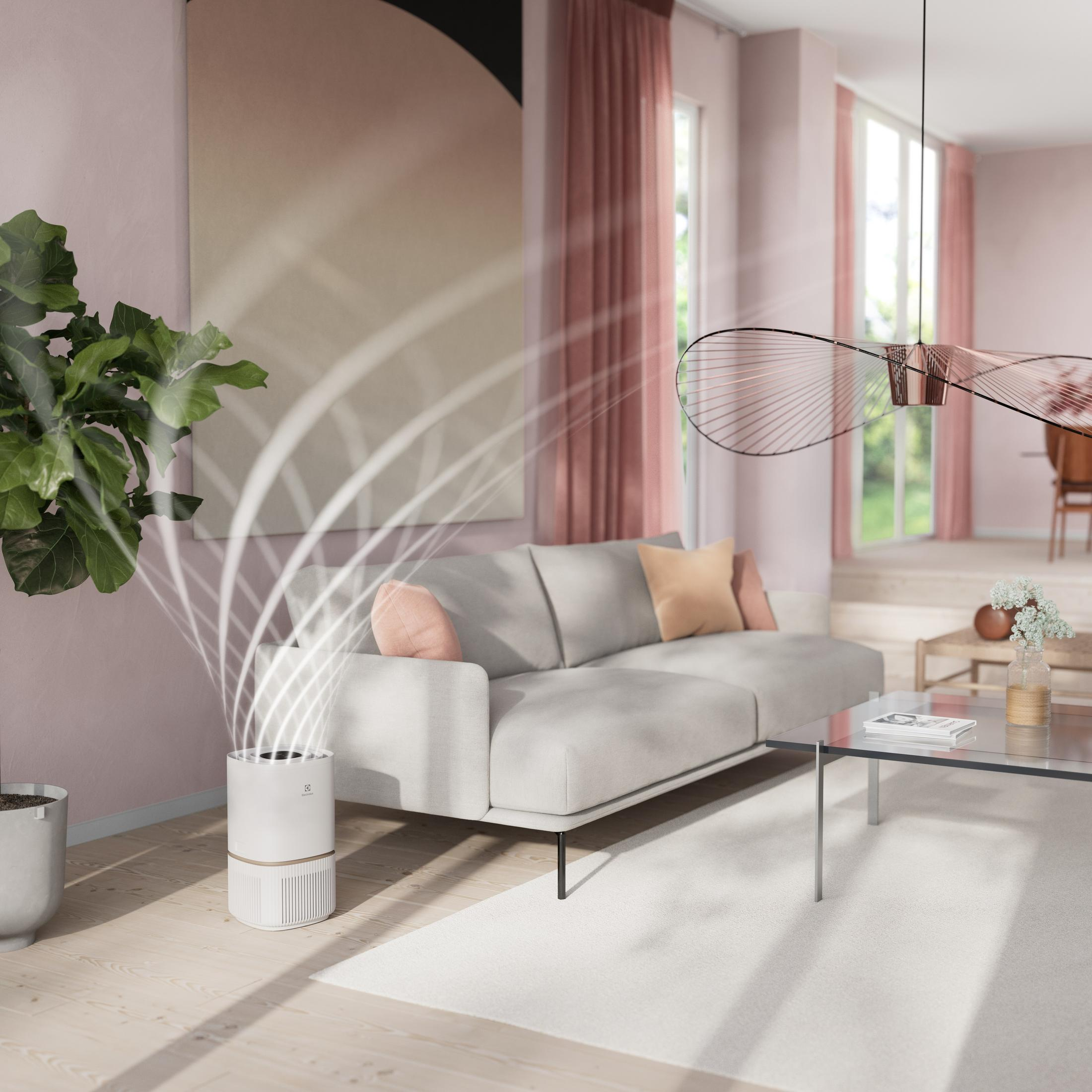 Ein weißer Luftreiniger mit Holzrand gibt Luftströme ab, neben einem Sofa.