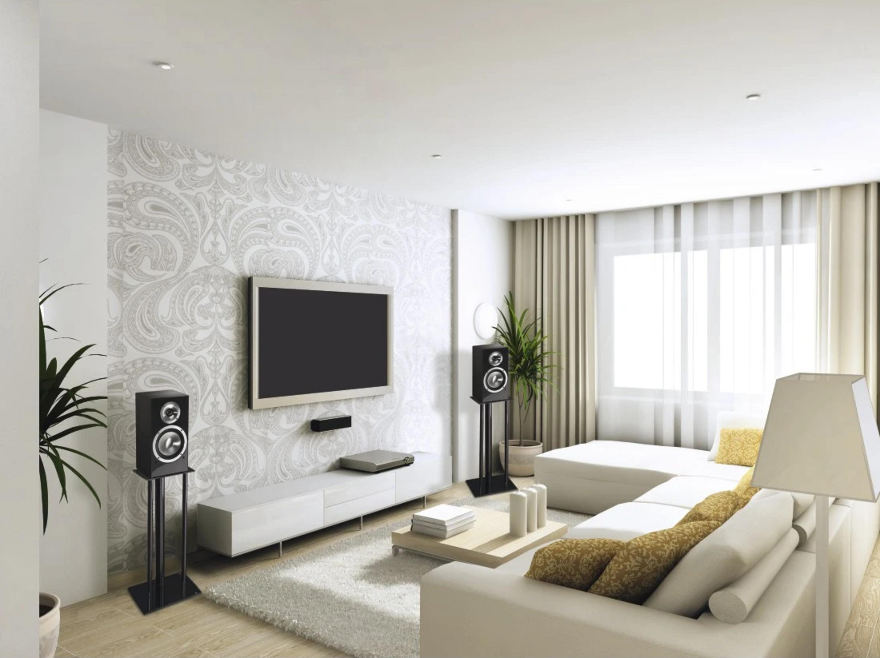 Ein modernes Wohnzimmer mit weißen Sofas, einem Fernseher und Lautsprechern.