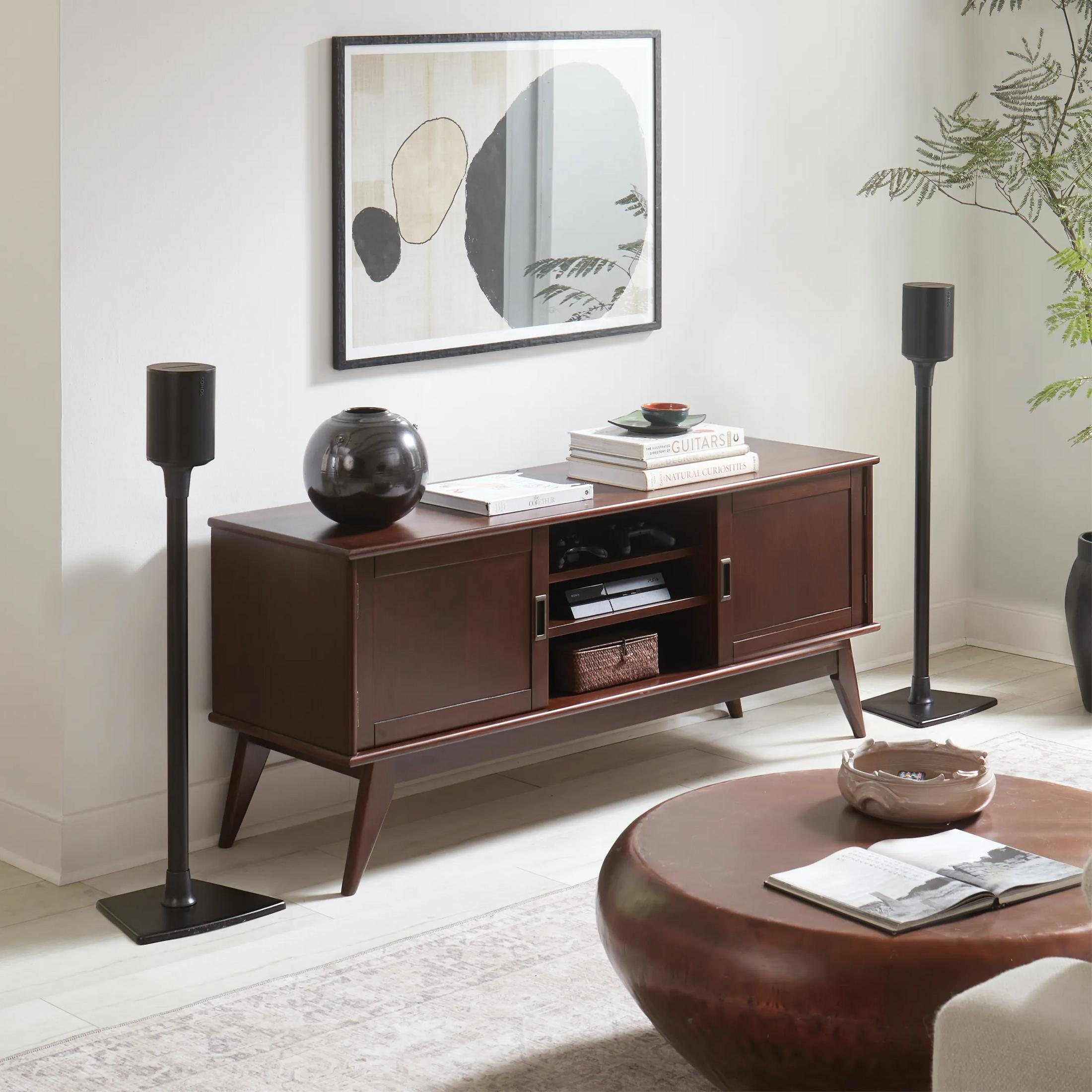 Ein dunkles Holzsideboard mit Kunst und Lautsprechern in einem modernen Wohnzimmer.