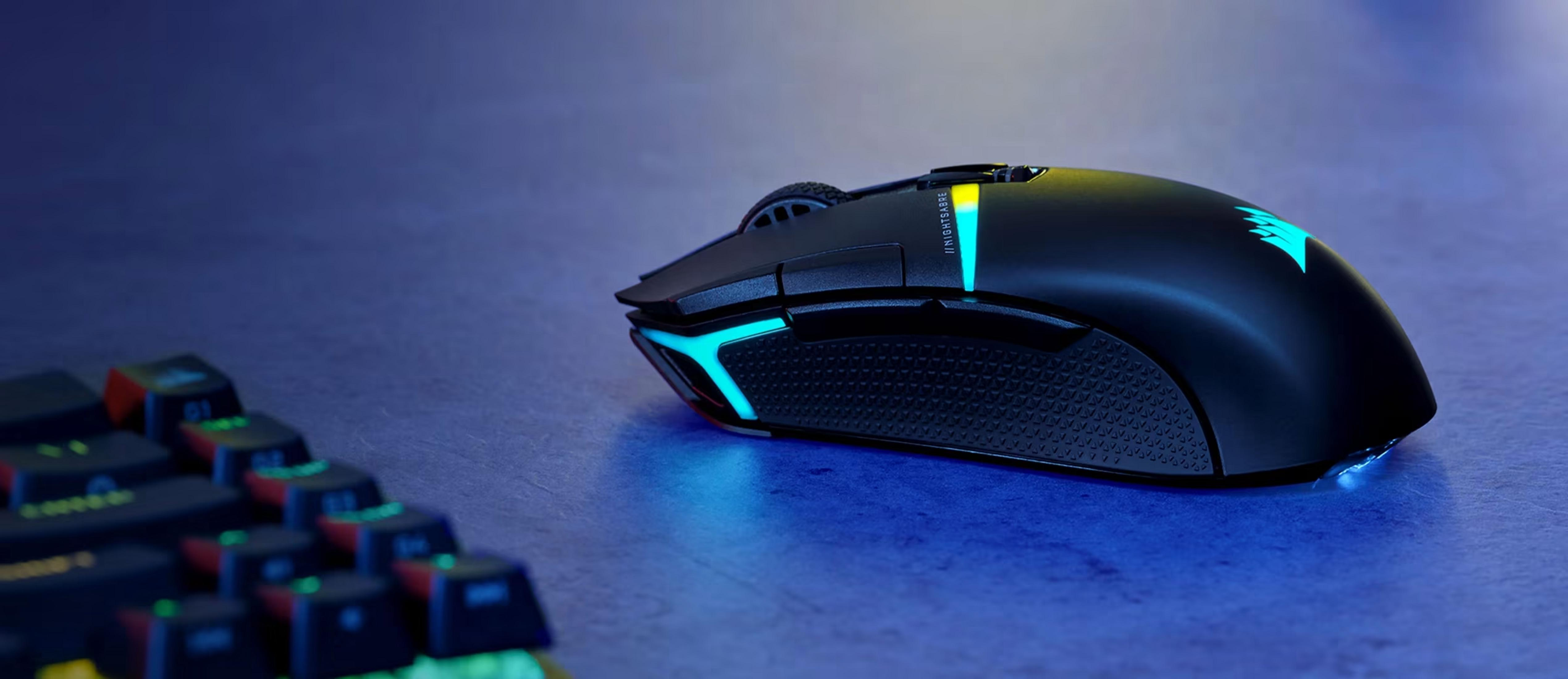 Czarna mysz gamingowa z niebieskimi i żółtymi światłami obok klawiatury.
