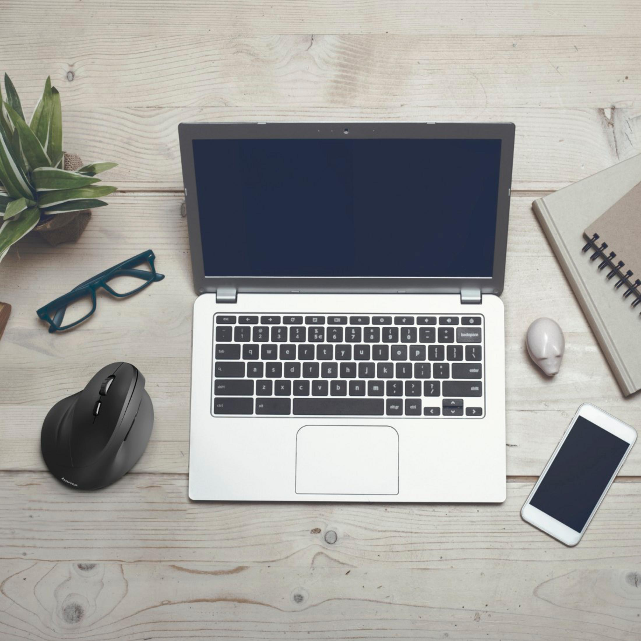 Laptop, mysz, okulary, roślina i telefon na drewnianym biurku.