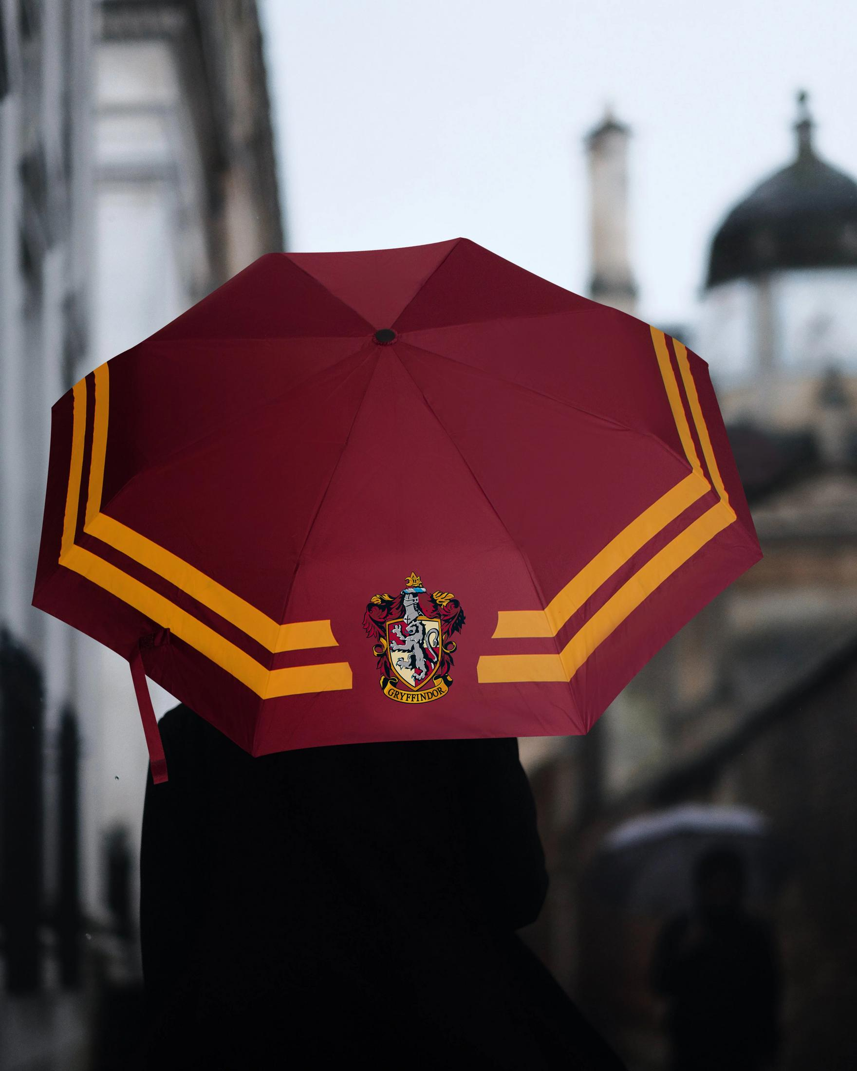 Un paraguas granate con el escudo de Gryffindor y rayas amarillas.