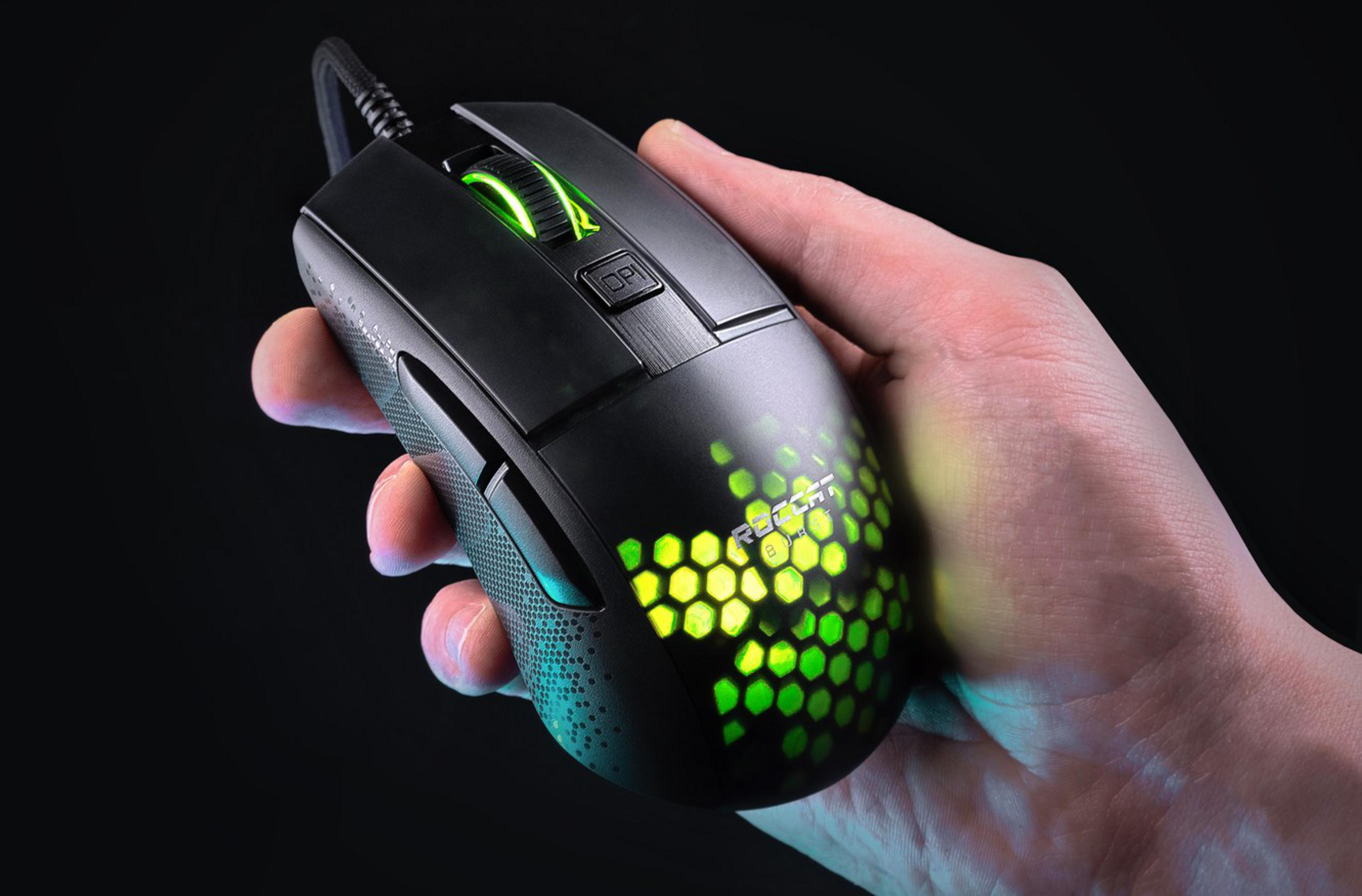 Dłoń trzyma czarną mysz gamingową z zielonym podświetleniem.