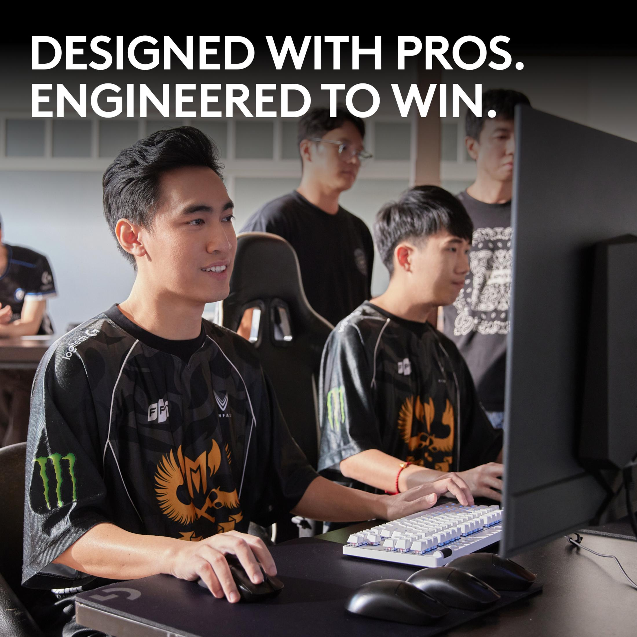 Gracze e-sportowi w koszulkach grają w gry wideo na komputerach, z tekstem na górze.