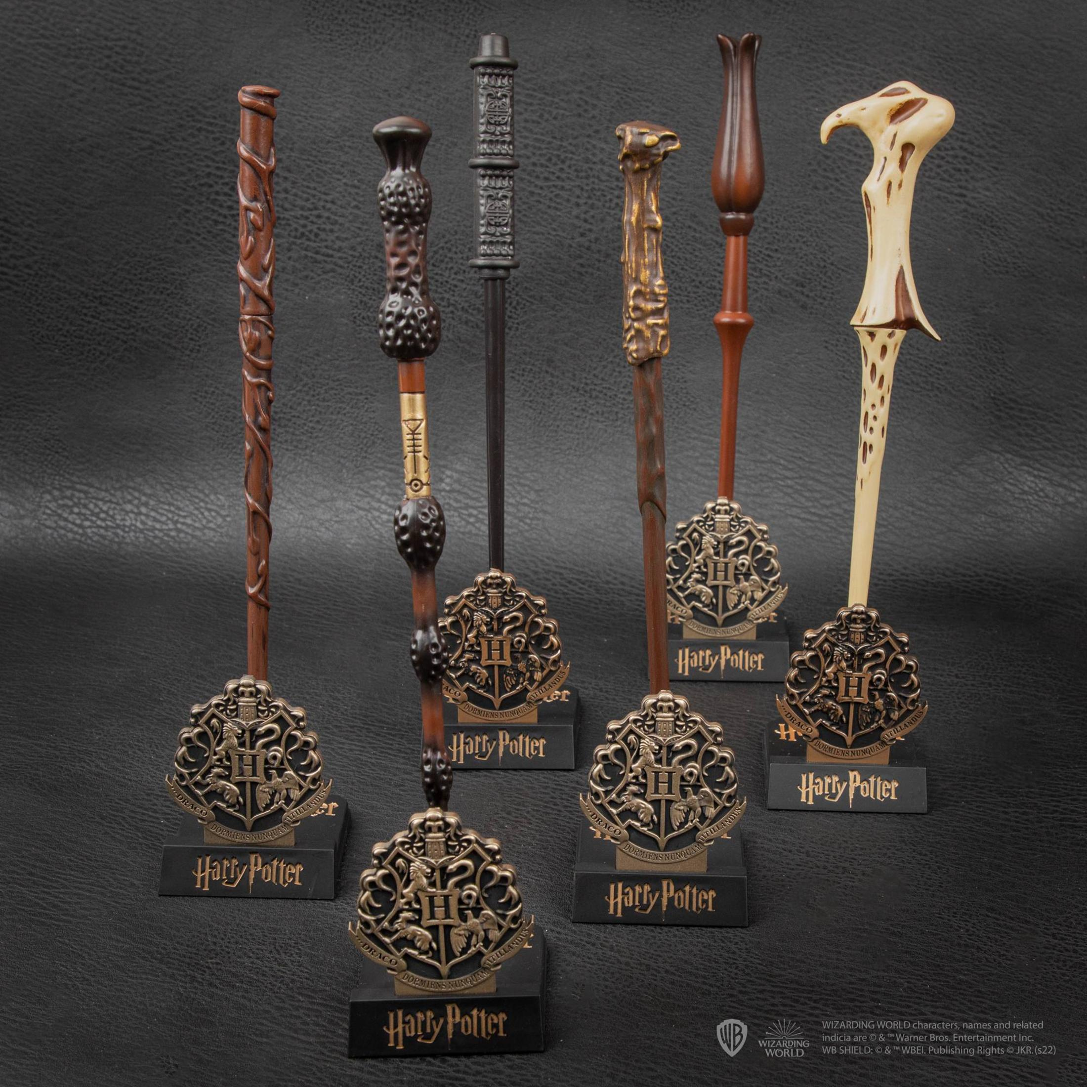 Sieben Harry Potter Zauberstäbe auf einem schwarzen Hintergrund. Jeder hat ein Emblem.