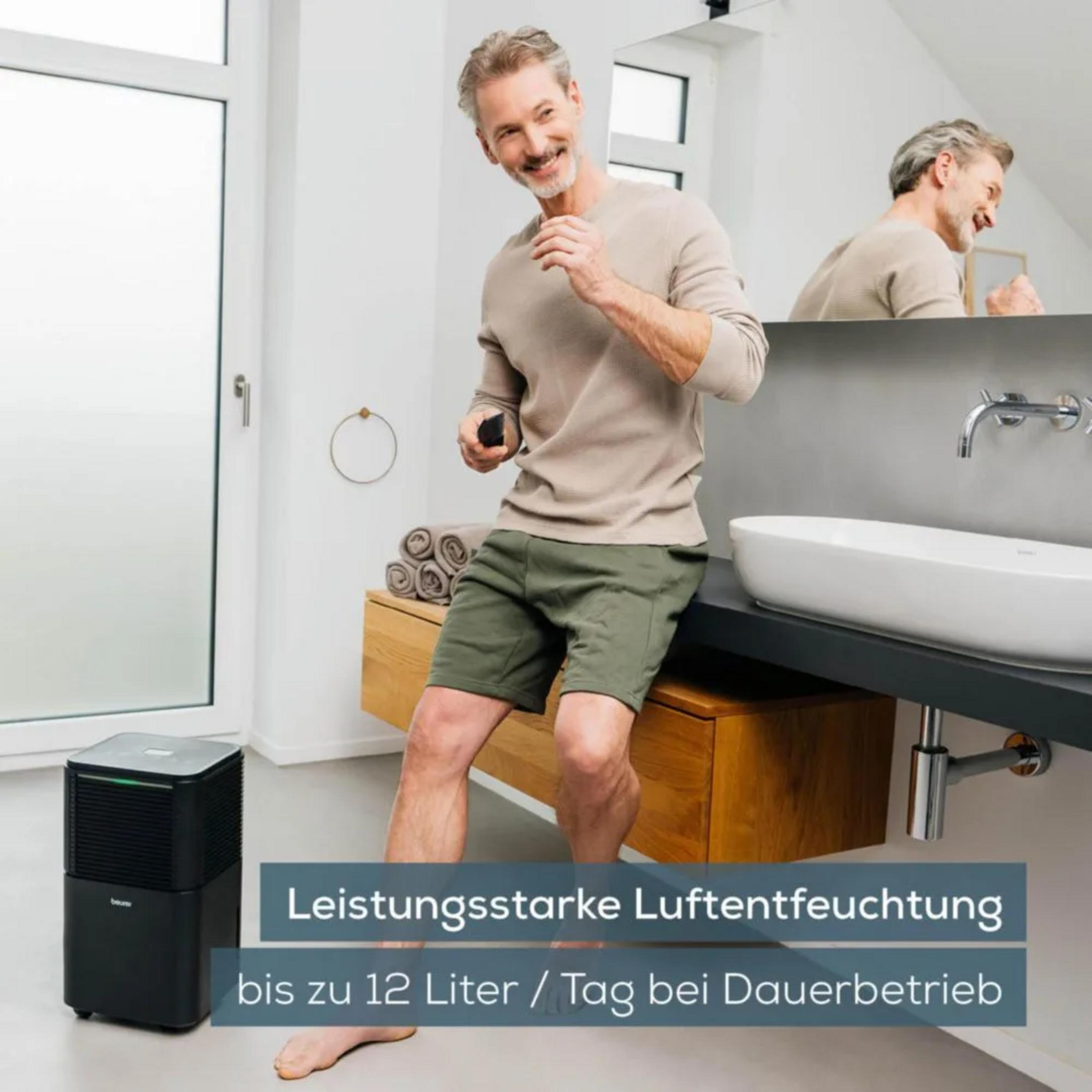 Man in badkamer met luchtontvochtiger, naast een wastafel.