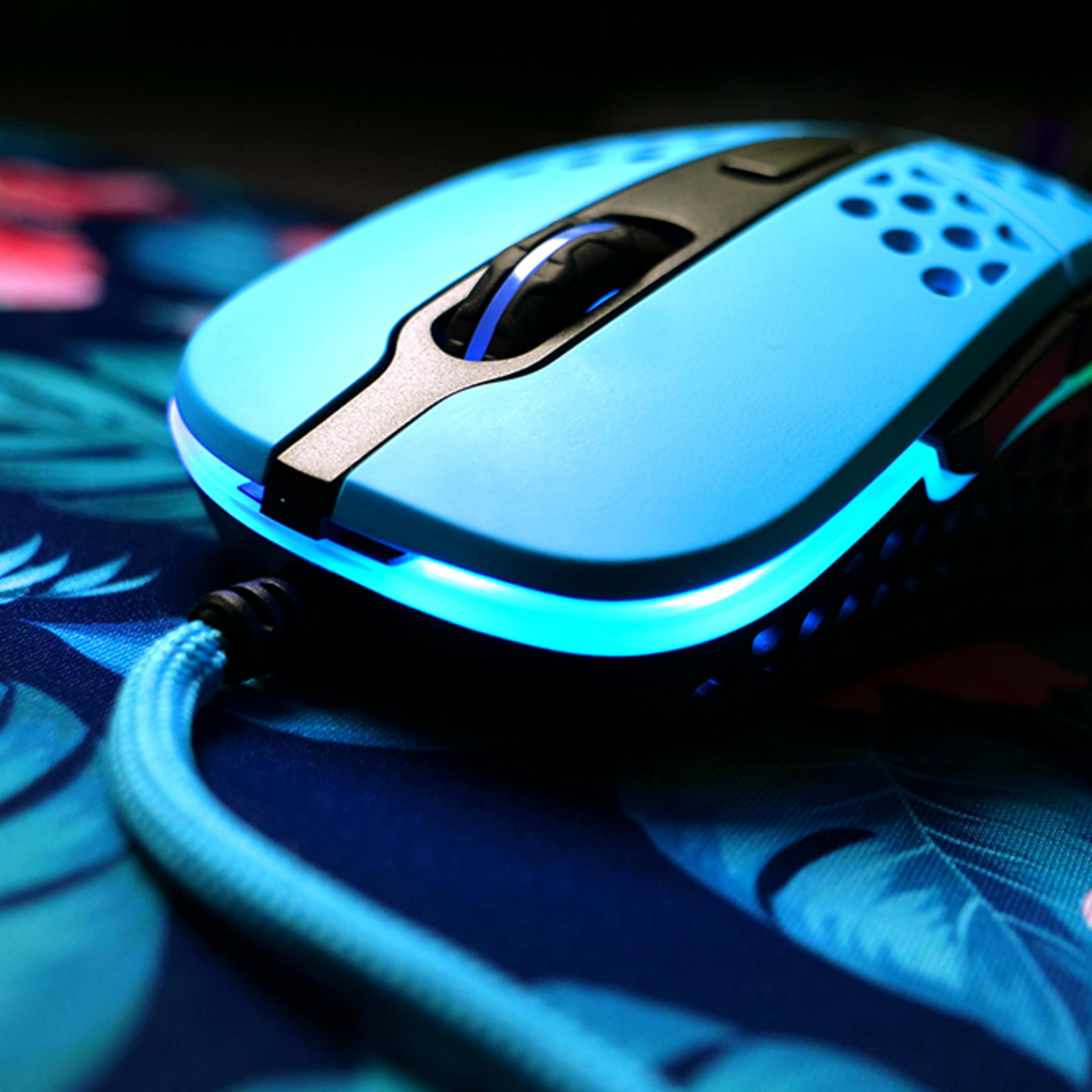 Un mouse gaming blu chiaro con illuminazione RGB poggia su una superficie.