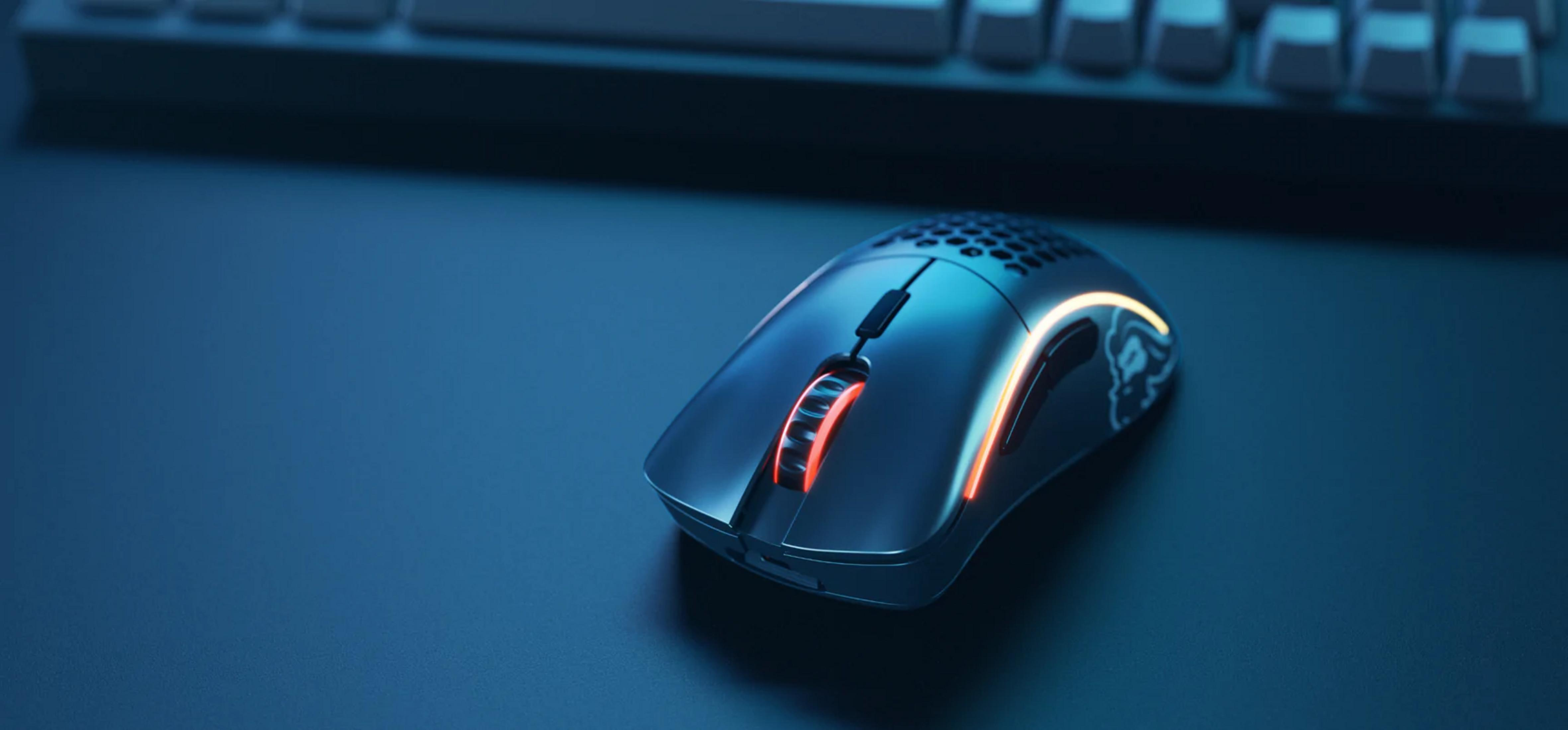 A black gaming mouse with red and yellow lighting on a blue desk.