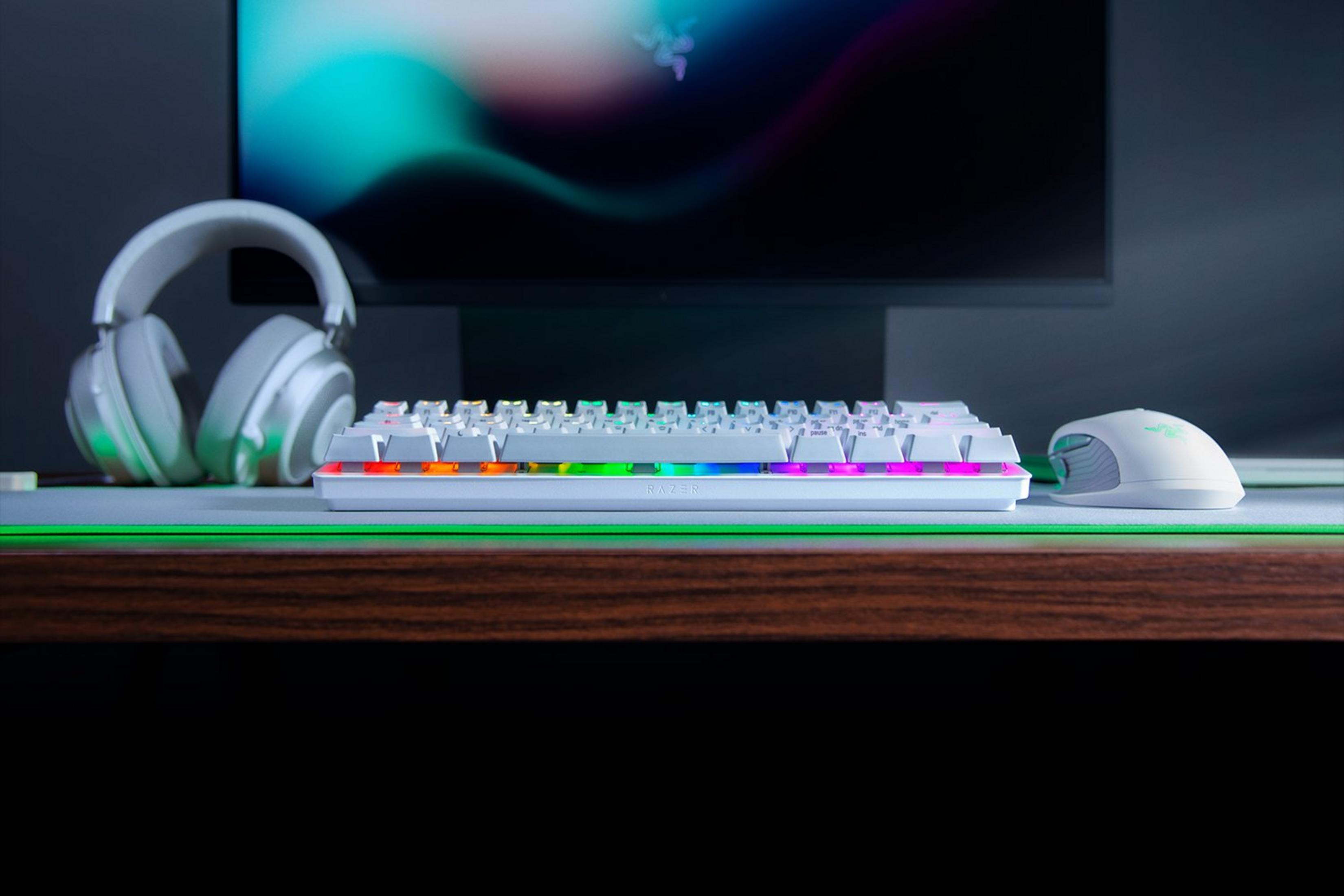 Weiße Tastatur mit RGB-Beleuchtung, weiße Kopfhörer und Maus auf Schreibtisch.