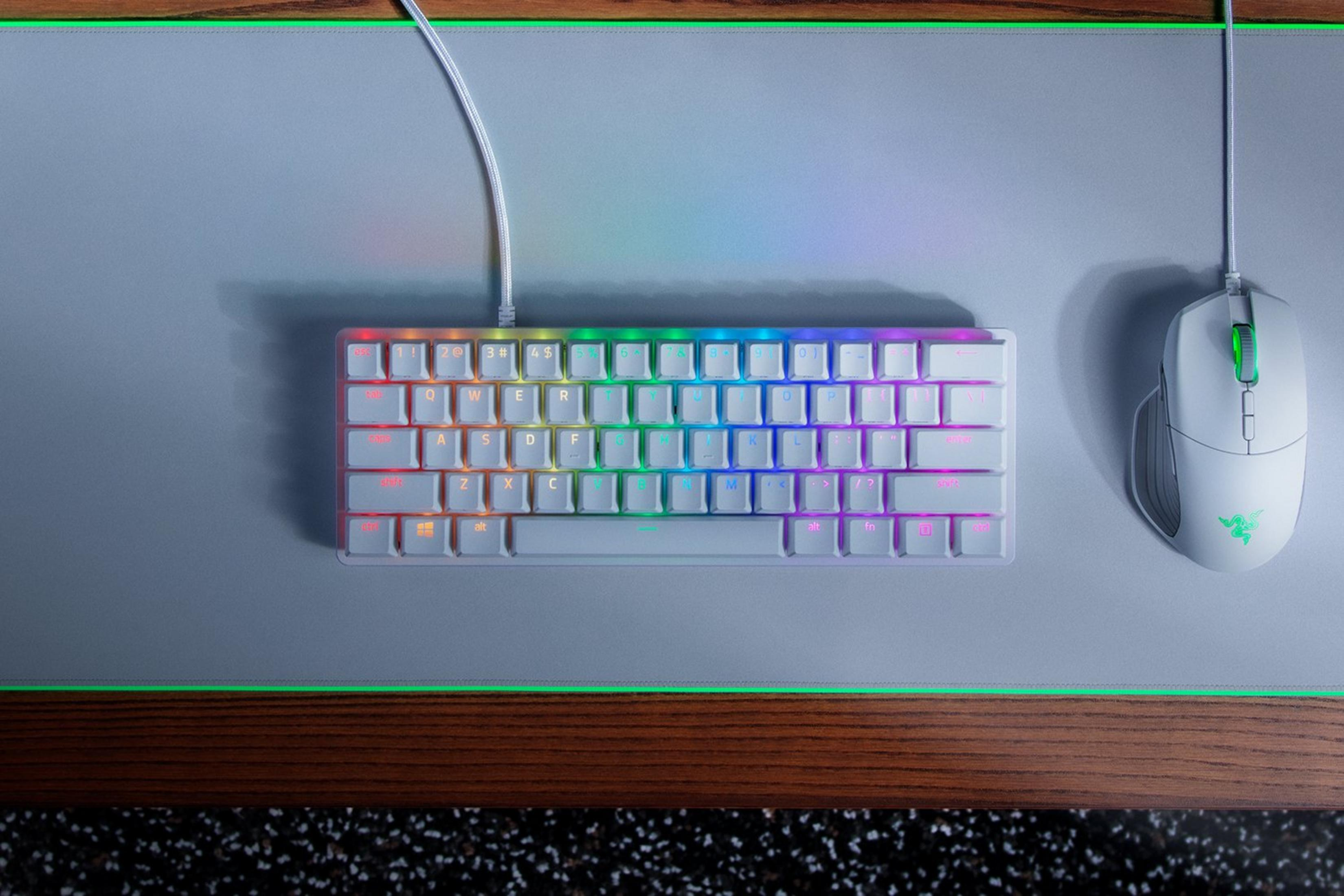 Eine weiße Tastatur mit RGB-Beleuchtung und eine weiße Maus liegen auf einer Matte.