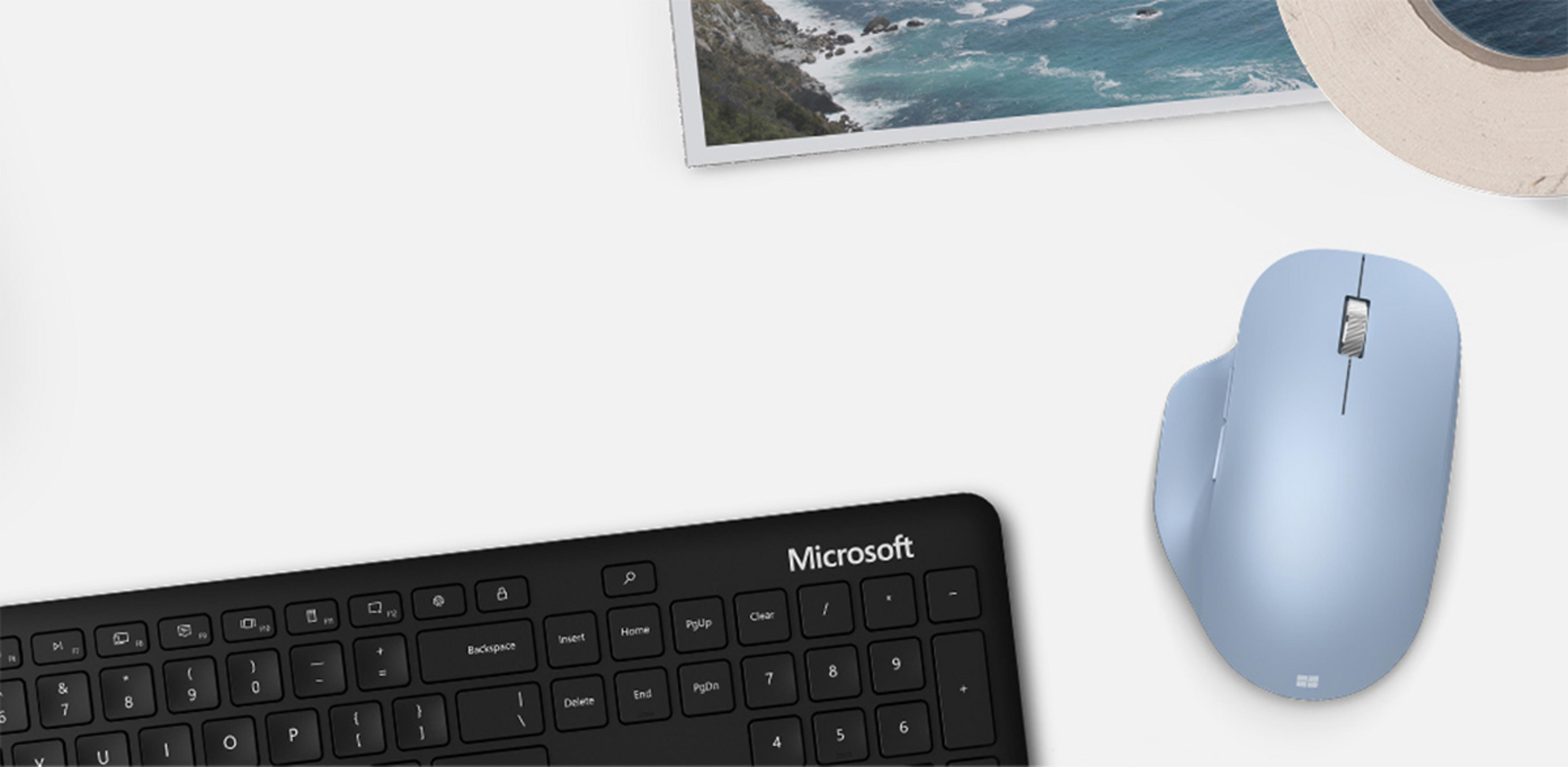Niebieska mysz Microsoft i czarna klawiatura na białym tle.